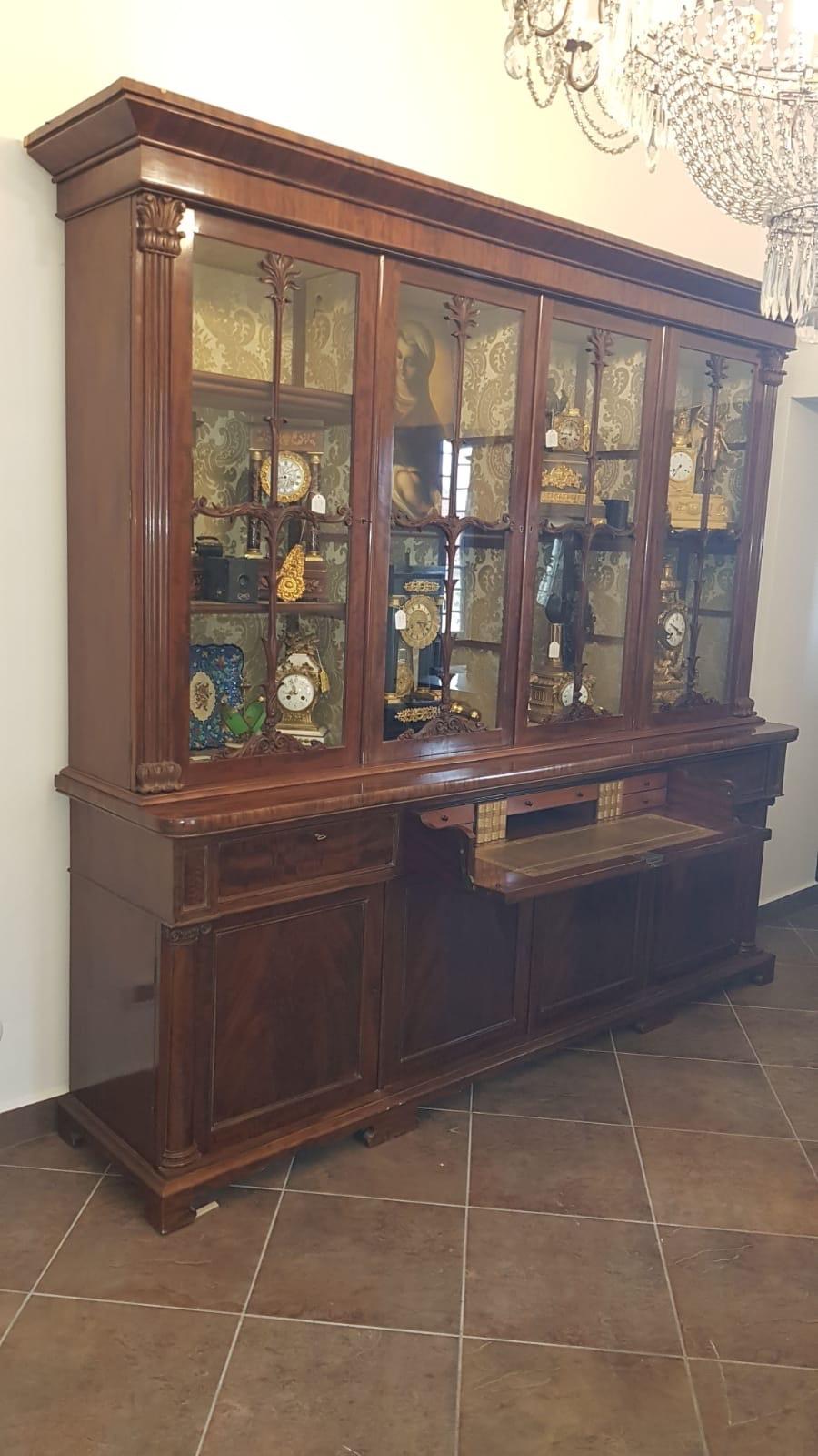 Irish bookcase in mahogany and mahogany feather, with carved capitals on the uprights of the doors, central flap drawer with internal drawers. Furniture of extreme beauty and proportions that make it a light piece of furniture, not as heavy as some