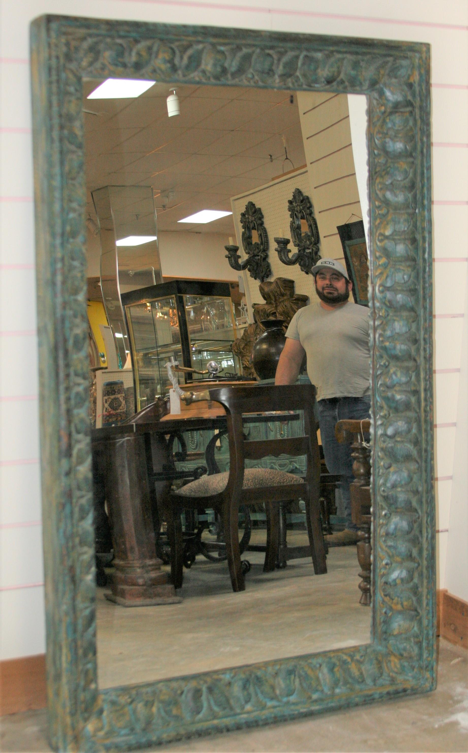 The mirror frame comes from a 19th century colonial home. It is highly carved and painted in turquoise green. It is made of fine teakwood. It is handcrafted and carved in old world carpentry. This is an extraordinary mirror that cannot be matched by