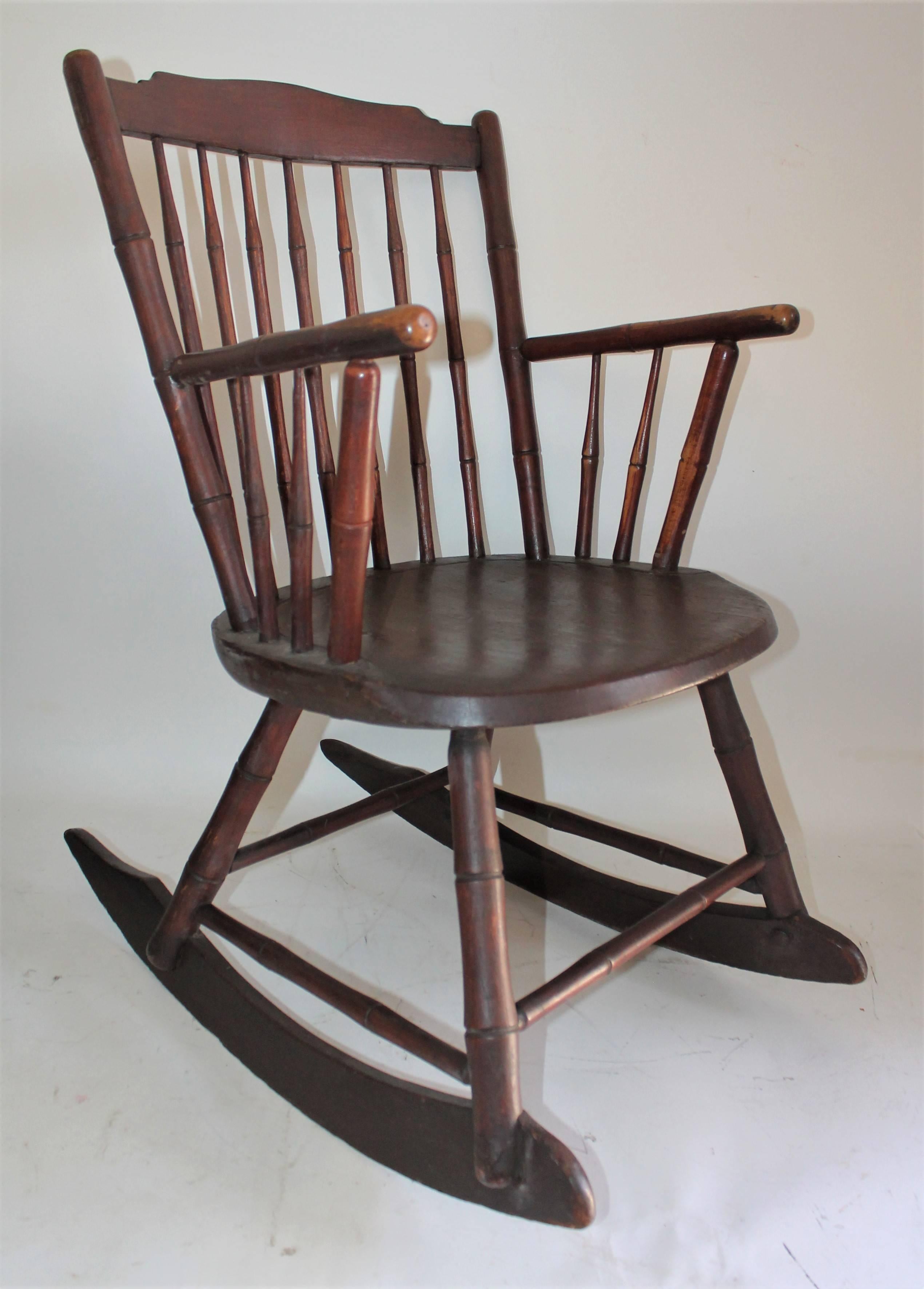 19th century windsor rocking chair in fine condition. This is a very sturdy rocking chair. Minor little old repairs. It has a wide seat and back. This rocking chair has a wonderful aged patina.