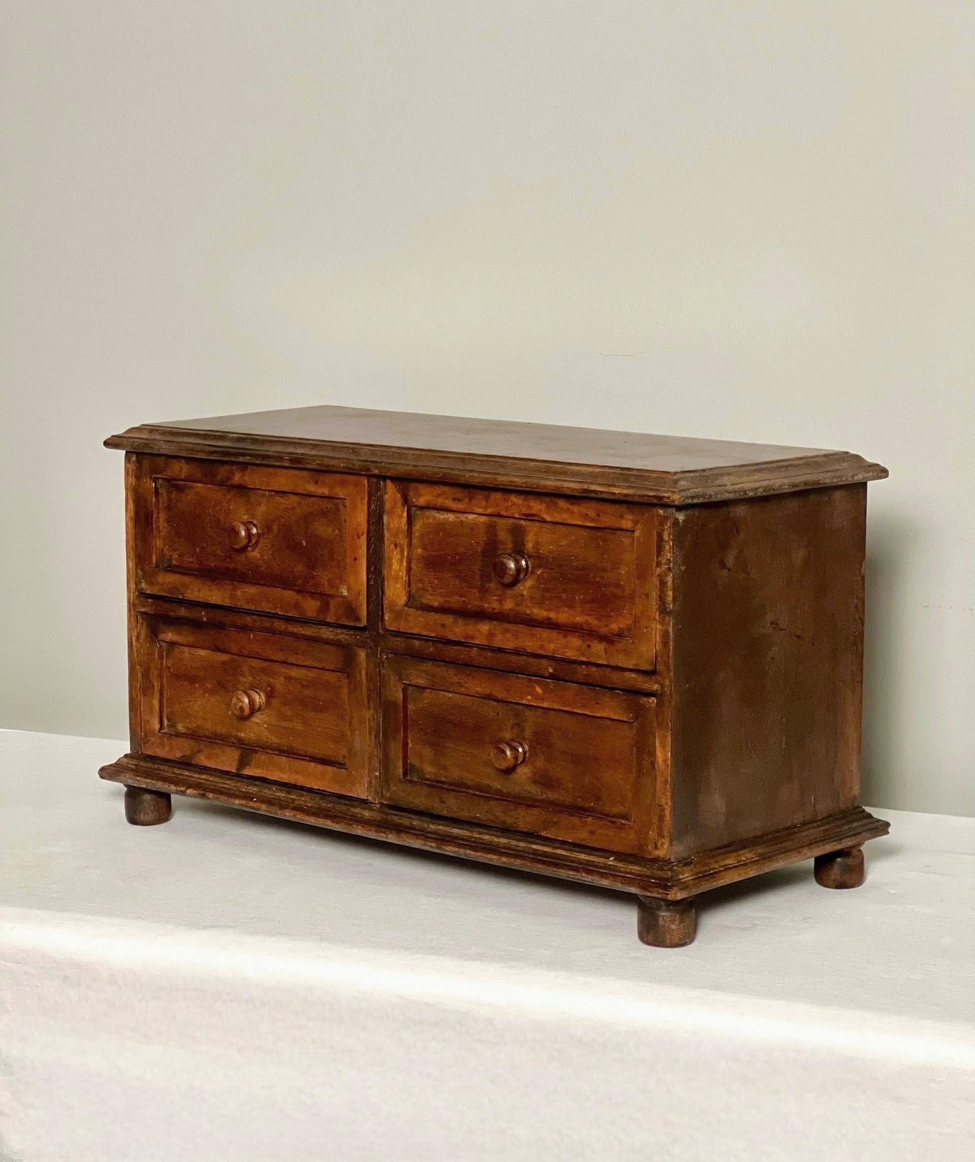Handcrafted antique small wood apothecary cabinet, mid to late 19th century. This is a versatile chest perfect to provide organization on a desk, countertop or worktable. A useful piece with a clean and classic design having four drawers with