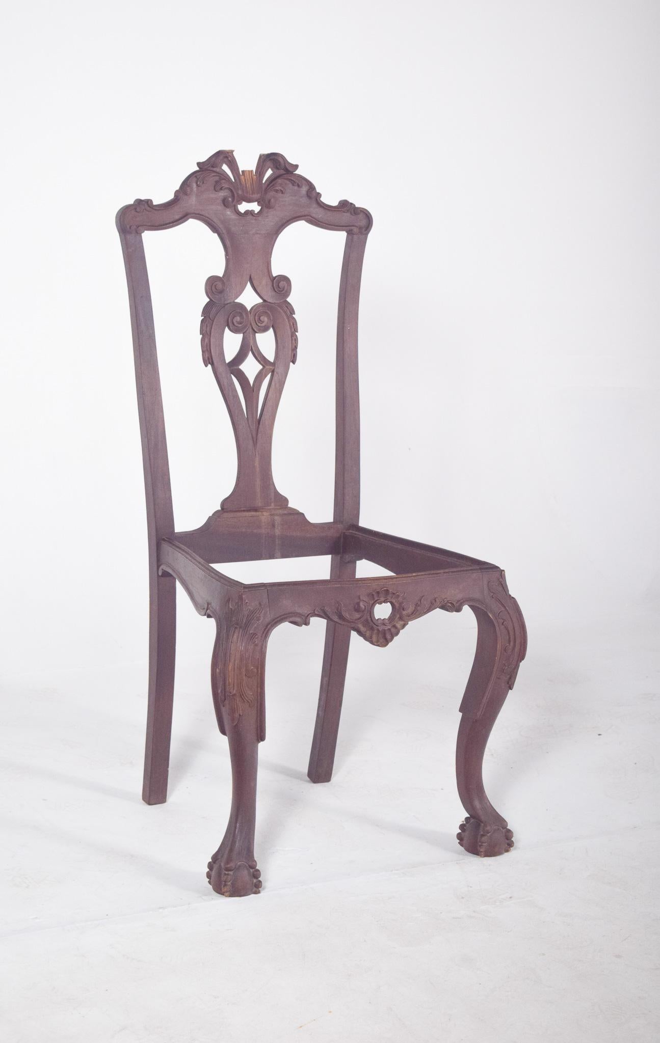 Sedia antica Chippendale. In legno nobile intagliato, si distingue per la ricchezza degli ornamenti e la grandezza formale. Lo schienale presenta un taglio sinuoso con intagli simmetrici di volute e foglie stilizzate, che culminano in un elemento