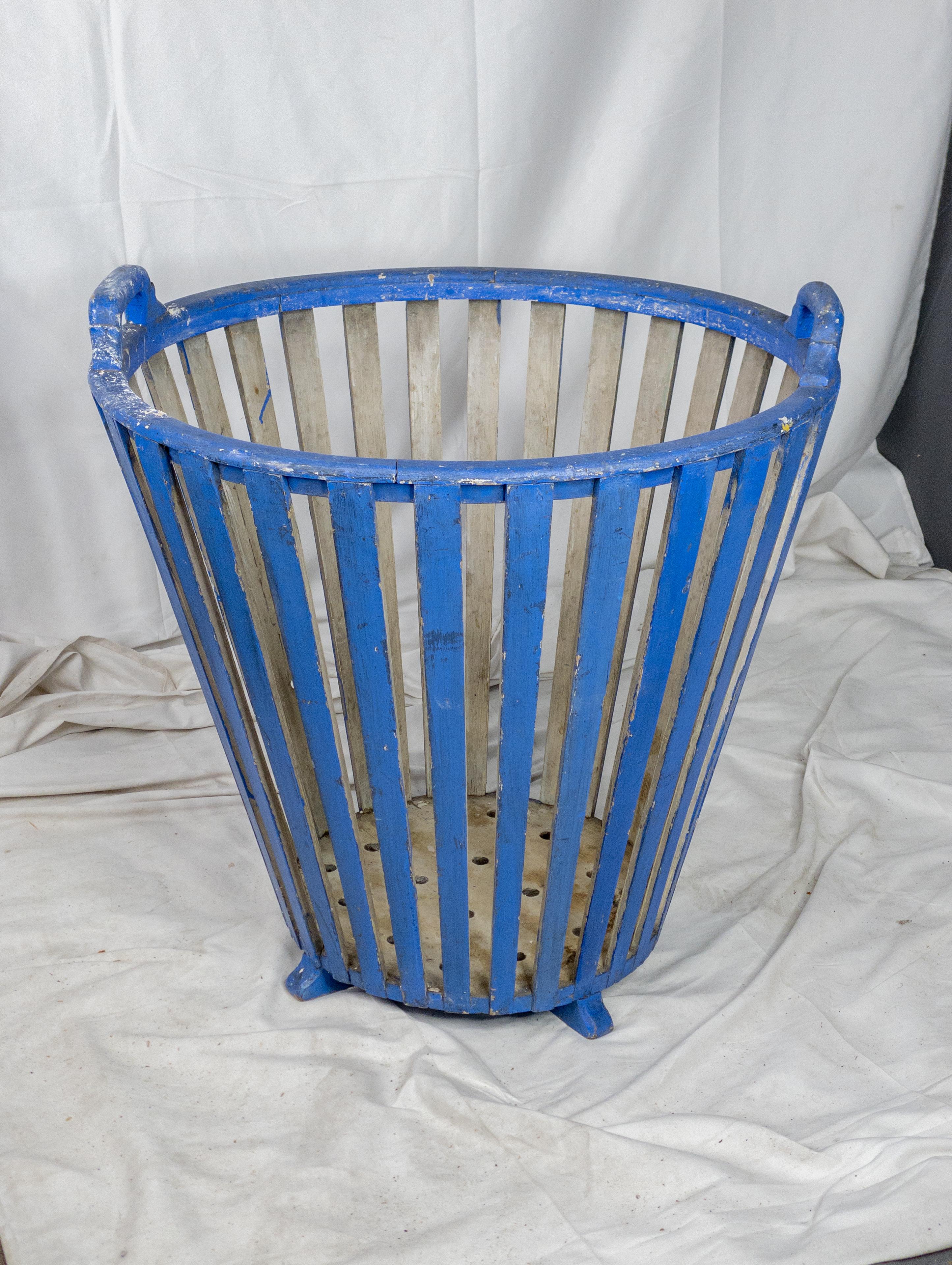 The 19th-century wooden basket is a charming example of rustic craftsmanship, painted in a faded blue hue that hints at its age and storied past. This basket is both practical and aesthetically pleasing, embodying the utilitarian design typical of