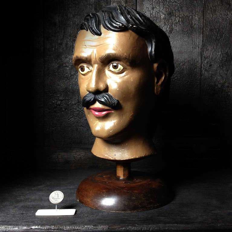 This is a very cool guy, it's a wooden head of a 19th century 'the Strongest Man of the World' attraction on a carnival or fair.
The brown color, or maybe the shape of his head, makes him a bit exotic too.
This head was probably used as an