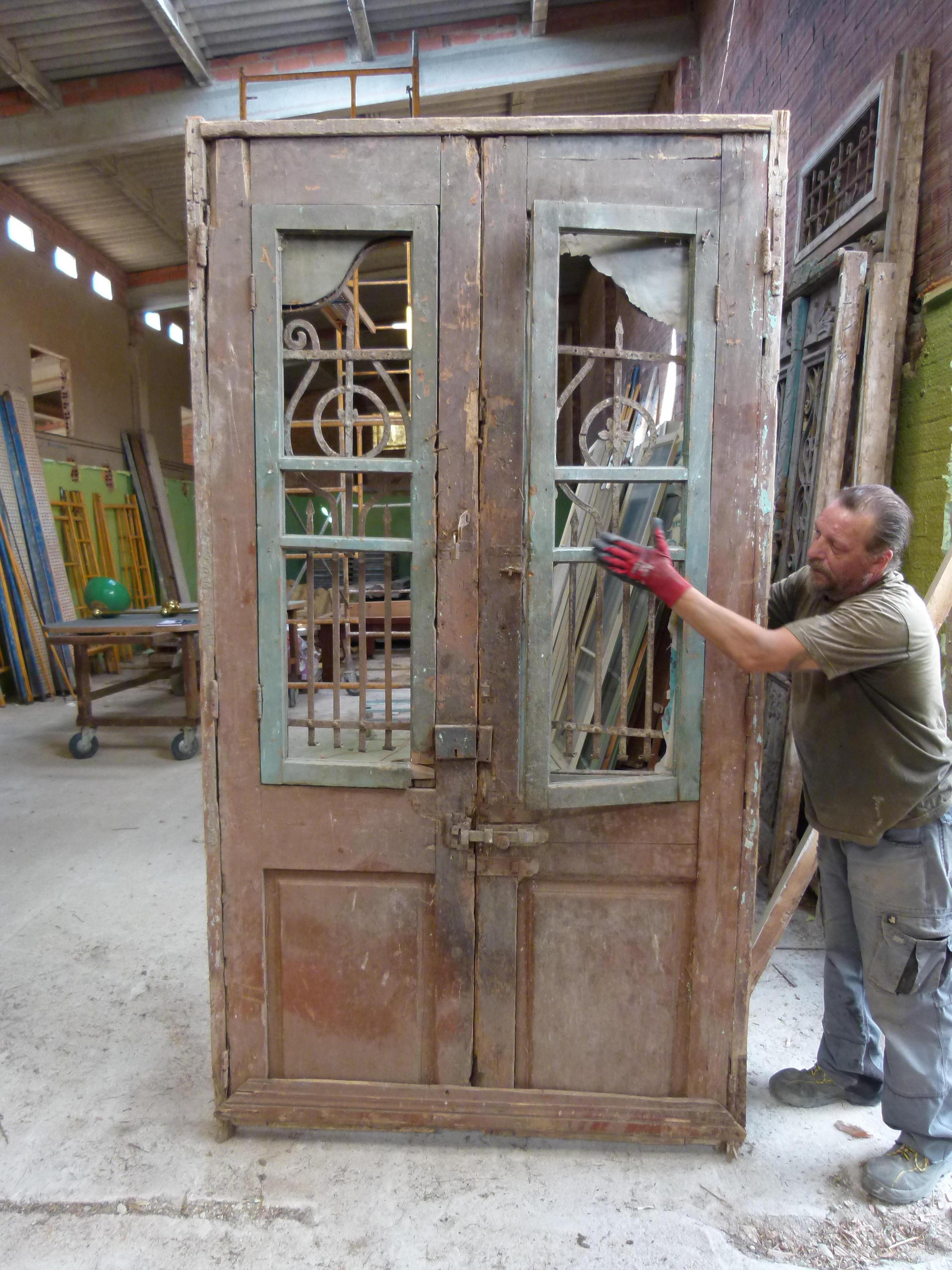 19th century double front door with patina in Art Nouveau style from Catalonien, Spain.
 Carved wood and cast iron typical from this period.
The door is framed and working but needs some restoration as some parts are damaged.
The original patina