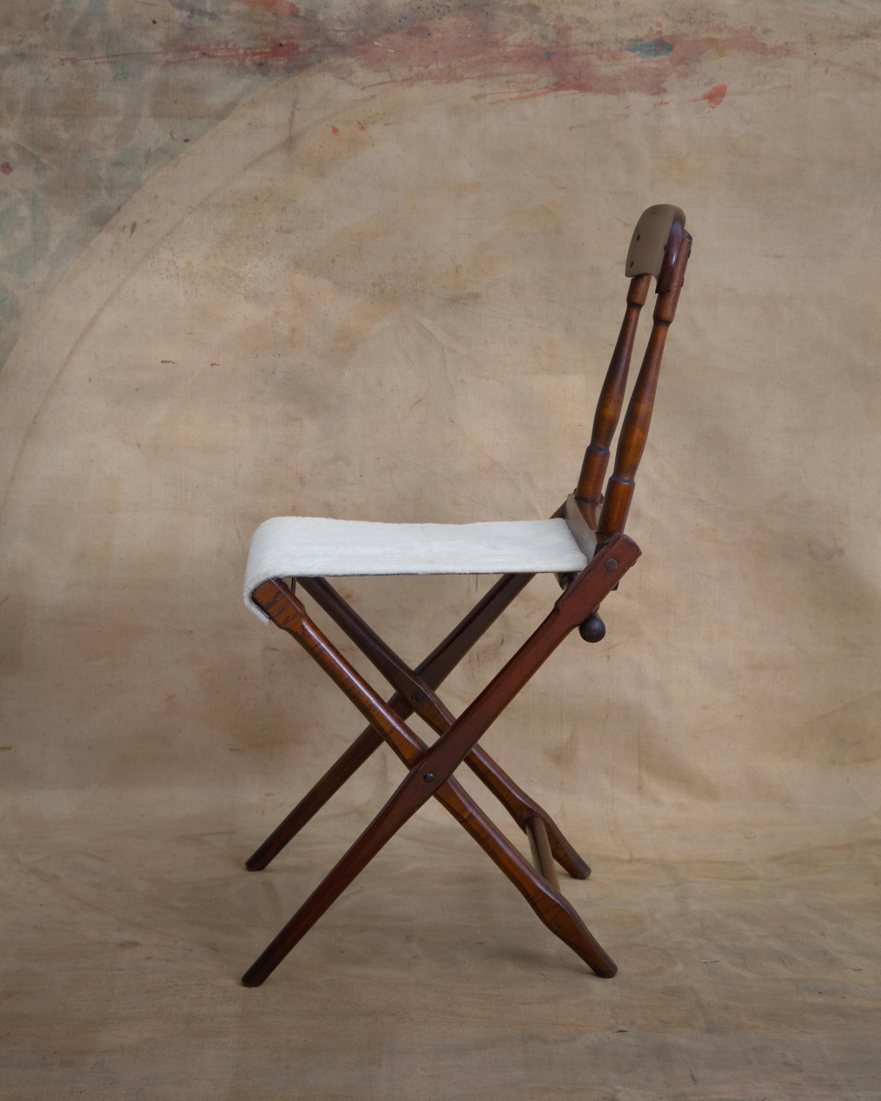19th century wooden folding campaign chair. Simply but elegantly designed and upholstered in shearling.