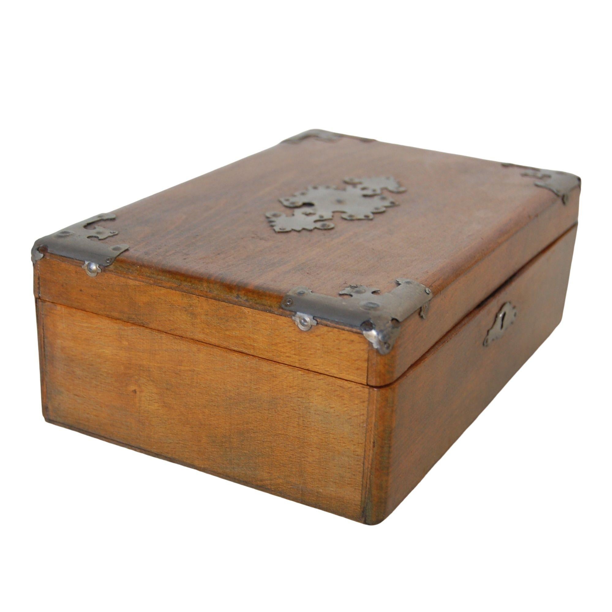 A stunning 19th-century wooden keepsake box adorned with intricate metal corner accents and a decorative center cut-out trim. The interior features elegant blue marbled paper lining, while the exterior boasts a classic skeleton keyhole. A timeless