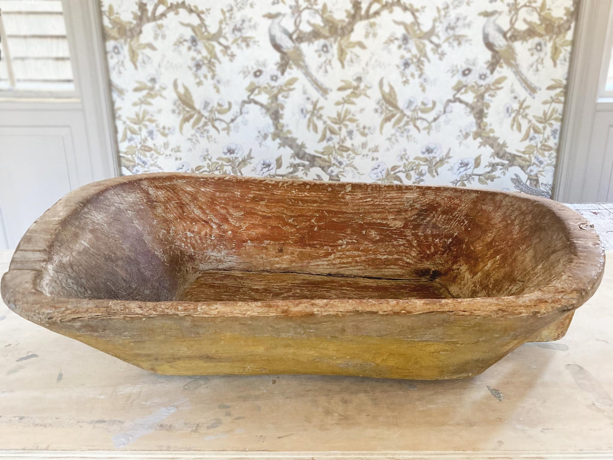 This large wooden trencher was hand-made in the 19th Century. It has a beautifully aged surface. We love the yellow paint that's been smoothed and worn over the years to reveal the rich, hand-carved textures underneath.

Dimensions:
28.5 in.