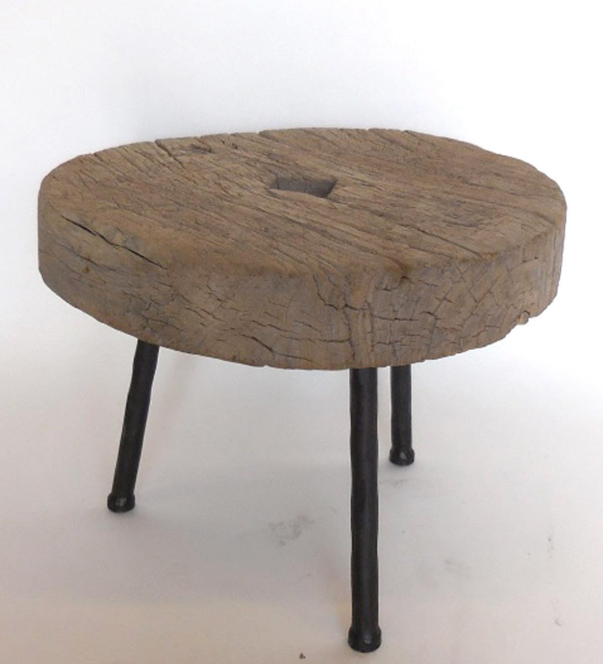 Rustic 19th century wooden elm wheel atop three contemporary hand forged iron legs. Wood shows natural patina and appropriate wear. Sturdy. Made by Dos Gallos Studio.