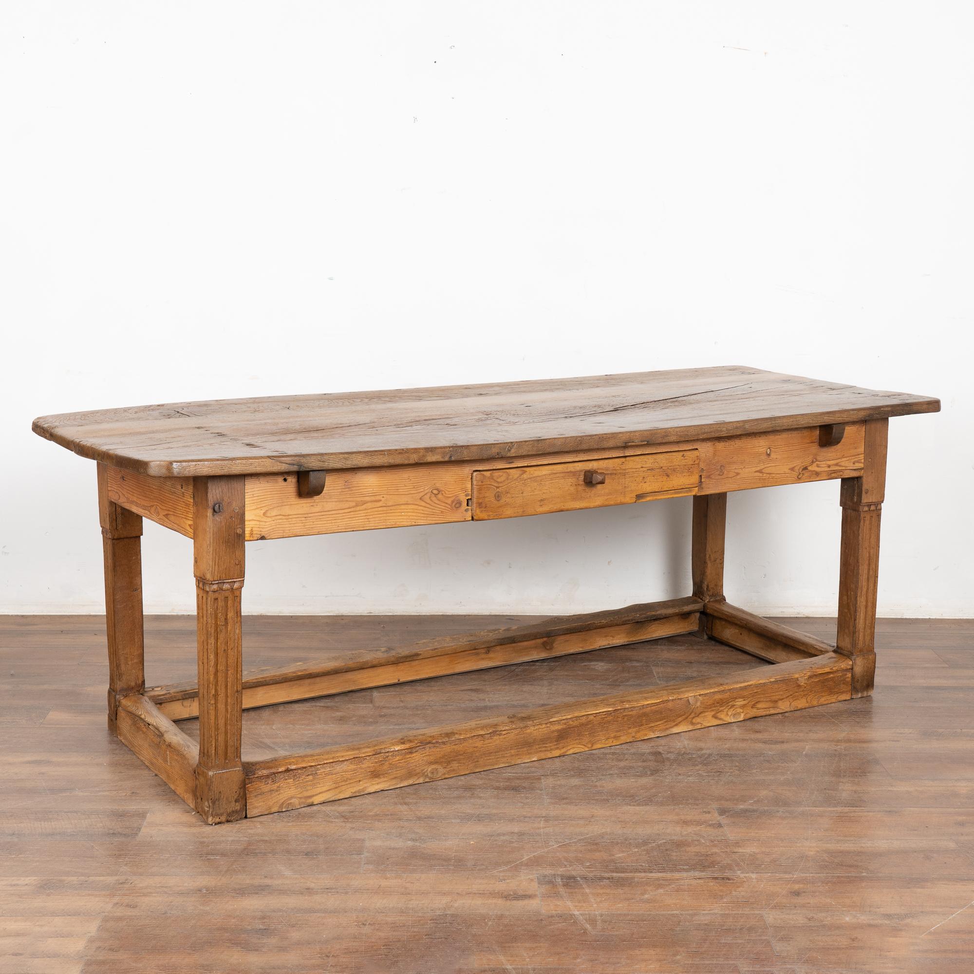 Cette ancienne table de travail est pleine de caractère grâce aux nouures, nœuds, entailles, gouges, fissures multiples et taches que l'on peut voir le long du plateau (et du châssis) et qui reflètent des générations d'utilisation.
Cette table de 7