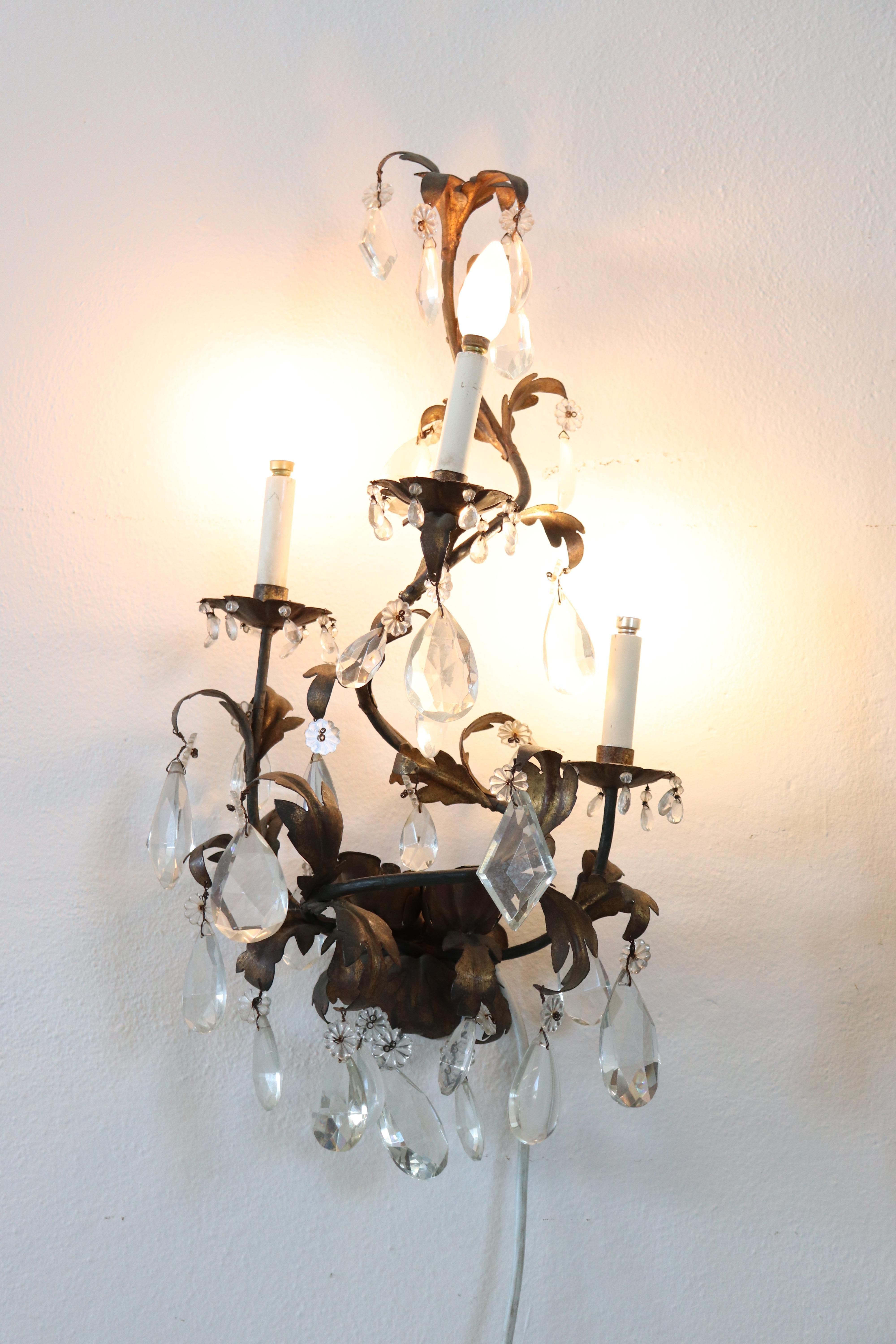 Beautiful and refined 1880s pair of wall lights three lights each. In wrought iron with a beautiful antique patina completely covered drops of crystal. The crystal exudes the typical brightness; the drops are finely worked giving an elegant light.