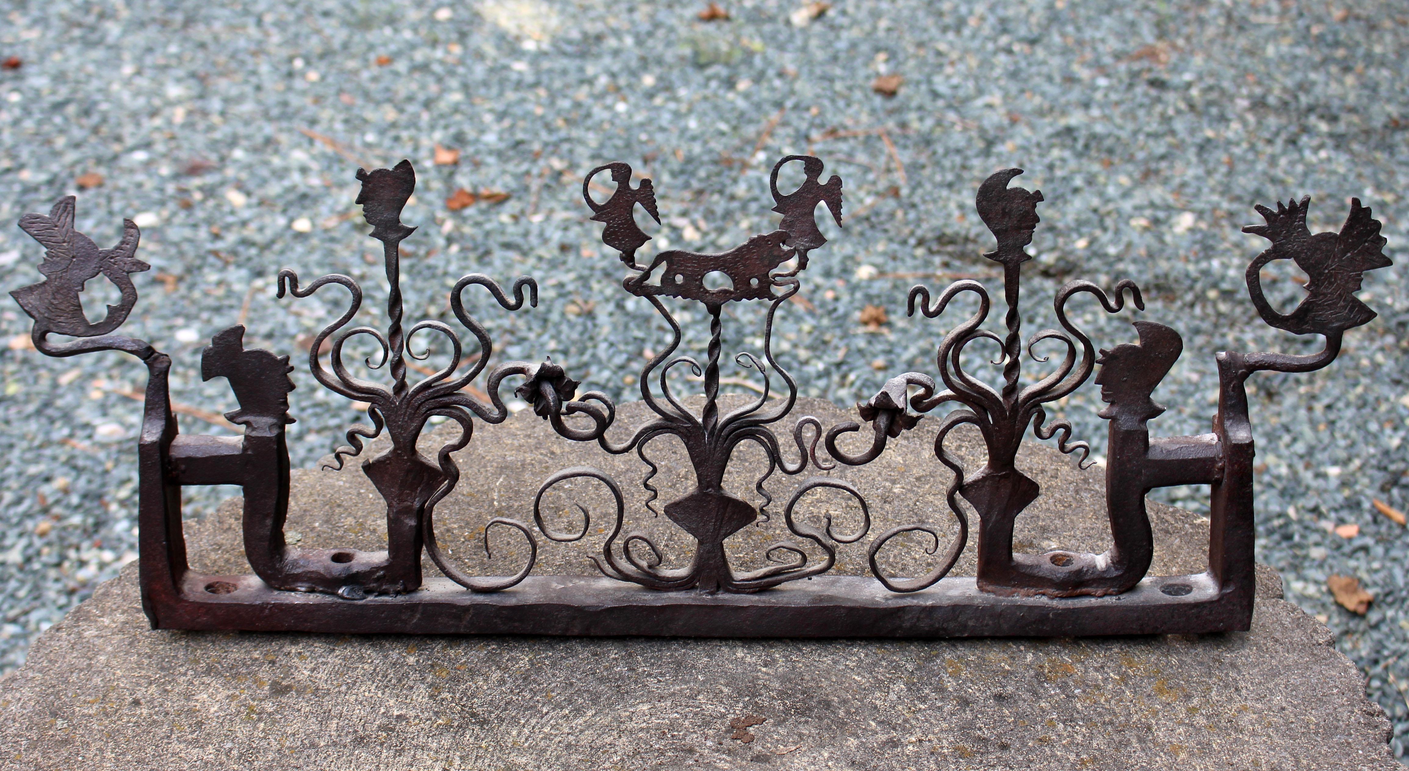 19th century wrought iron fence fragment, Continental likely Portuguese. Fancifully decorated with scrolls, helmeted busts, a pair of angels flanking a lion, etc. Fun in front of a fireplace, kitchen backsplash or accent decoration. Estate of Jean