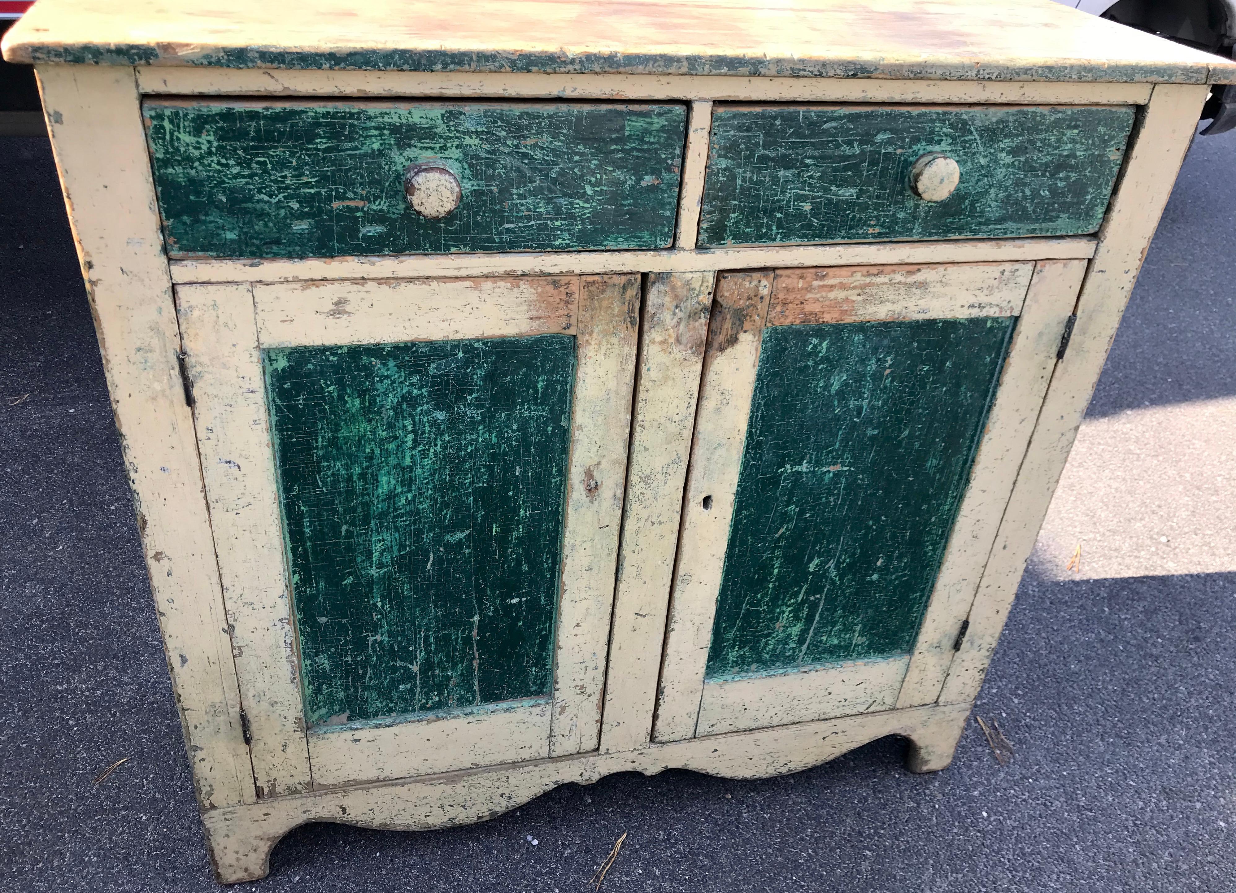 19th Century pine buffet in original yellow paint with contrasting green painted panels. Two side-by-side drawers over two doors with single shelf interior and nicely shaped skirt. Paint loss consistent with age and use.