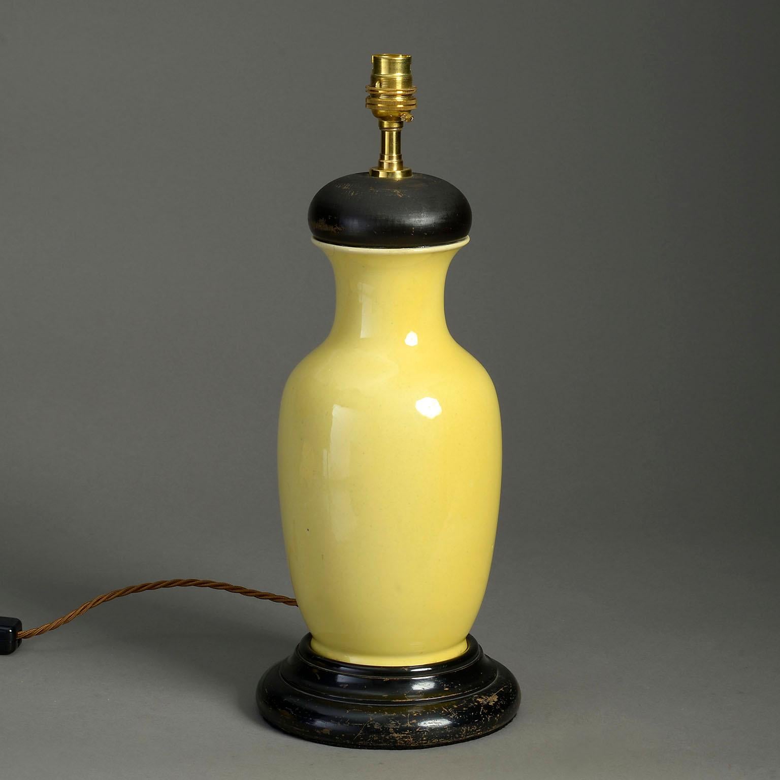 A late 19th century yellow glazed pottery baluster vase, mounted as a table lamp with turned ebonised cap and turned base.

