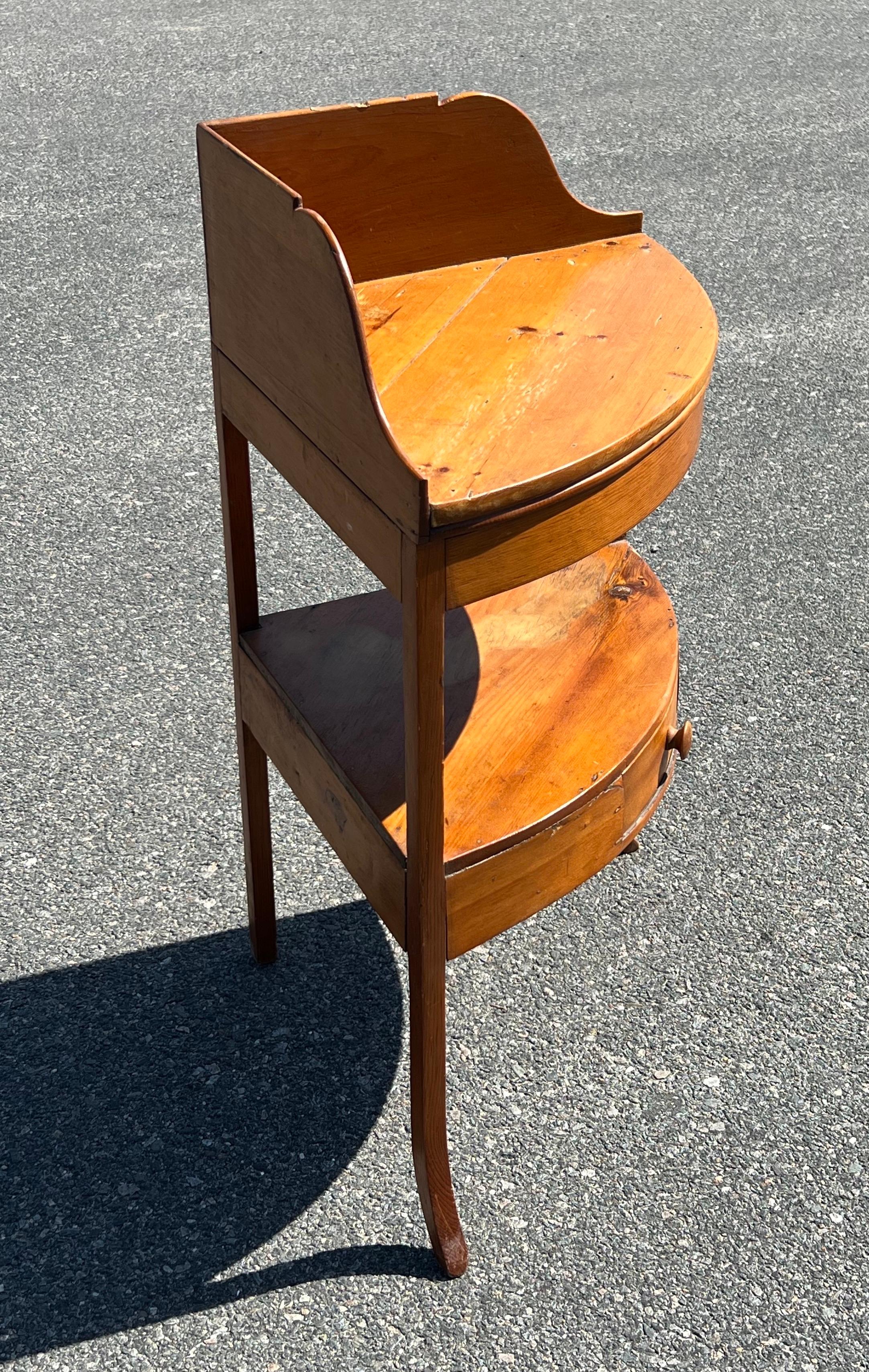19th century yellow pine two tier corner washstand with dovetail-joined backsplash, single lower drawer, and delicately shaped front legs. Surface height 30 inches, 17.75 inches depth on either side from corner out.