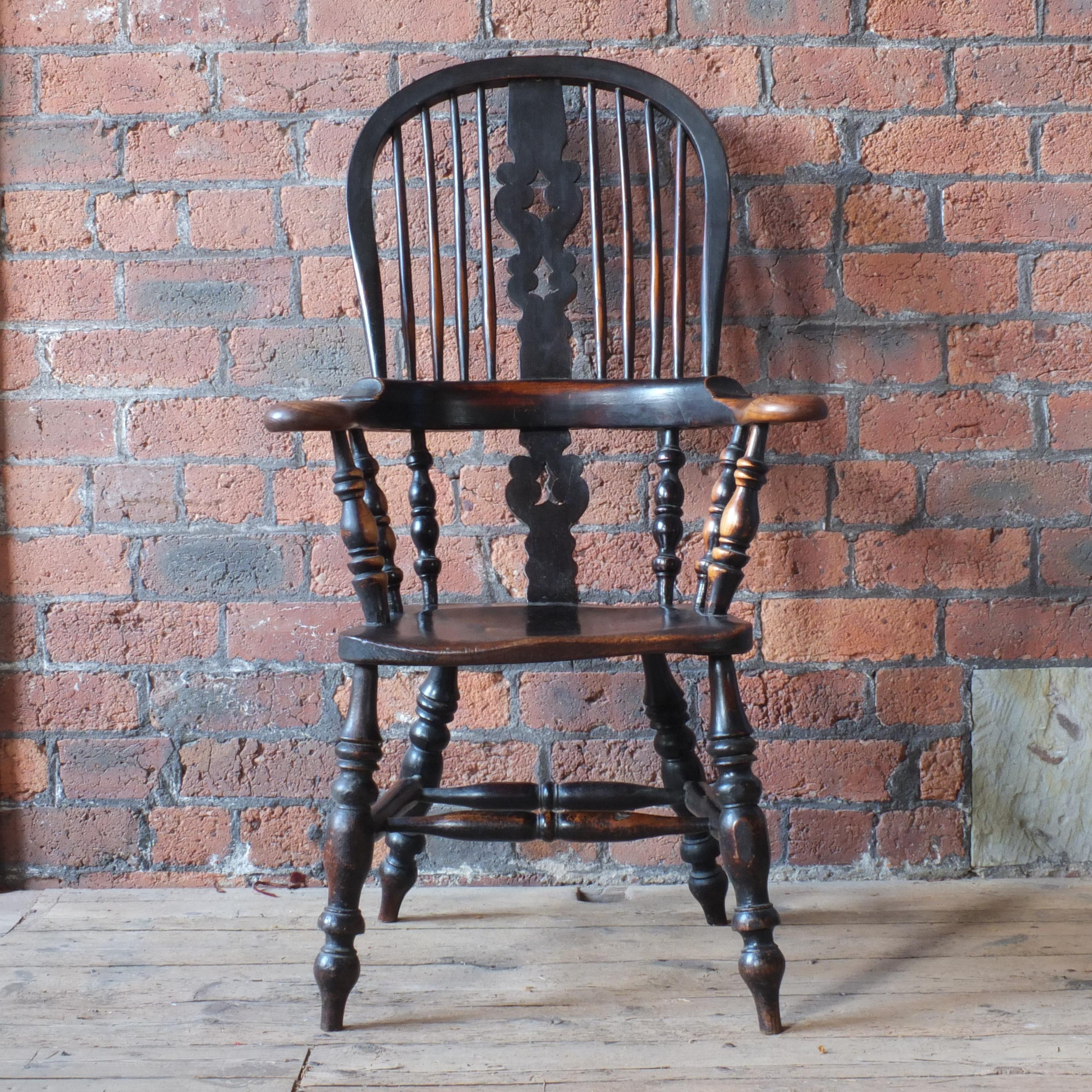 An ash with elm seat with a three piece arm bow sitting on nicely turned legs connected by a double H stretch. The wear and patina to the original black paint on this chair is absolutely gorgeous and such that only time and use can recreate!