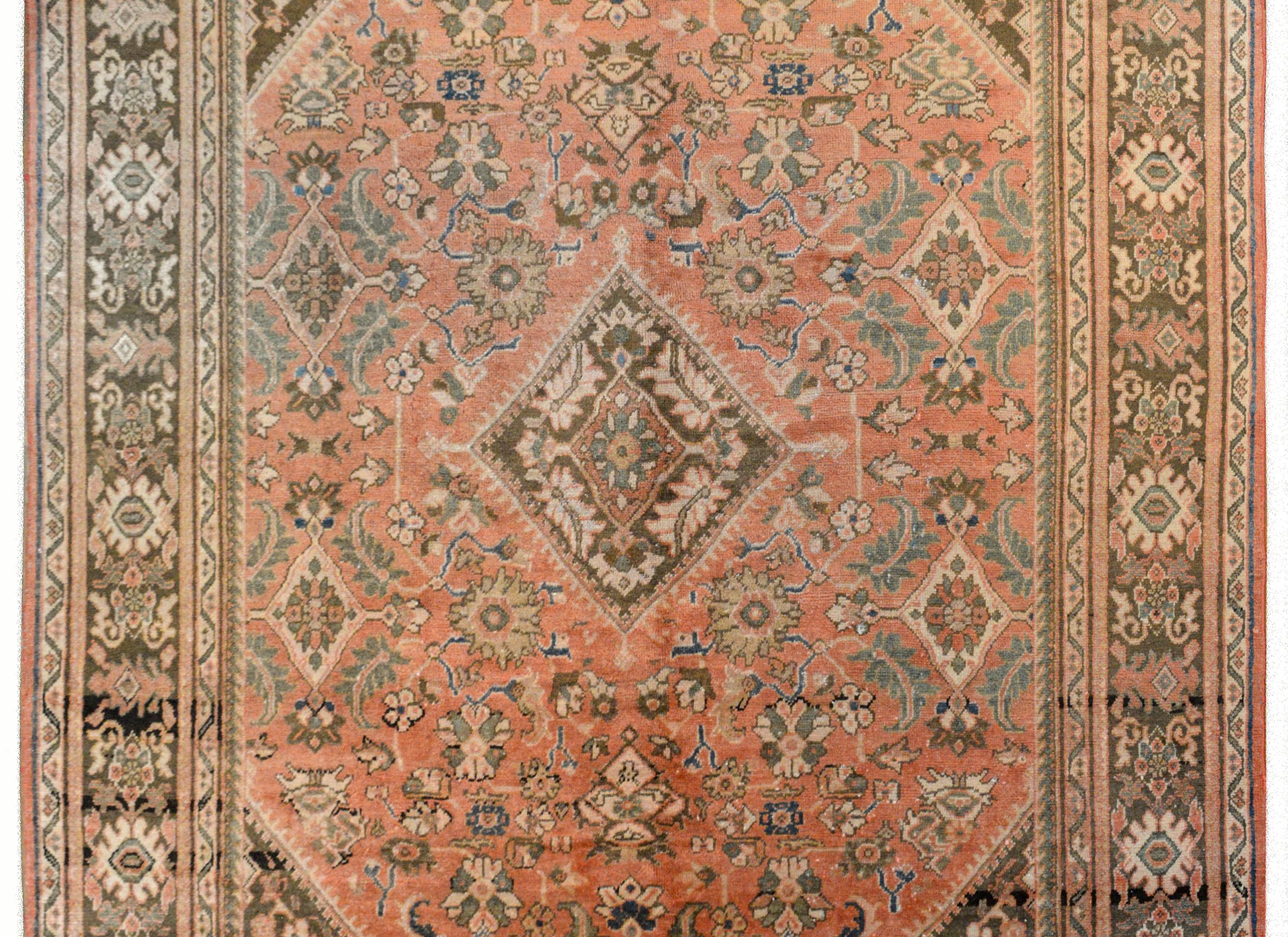 A fantastic 20th-century Mushkabad rug with a bold tribal pattern containing myriad flowers and leaves woven in varying shades of gray and taupe against a muted orange background. The border is strong with large-scale stylized flowers flanked by