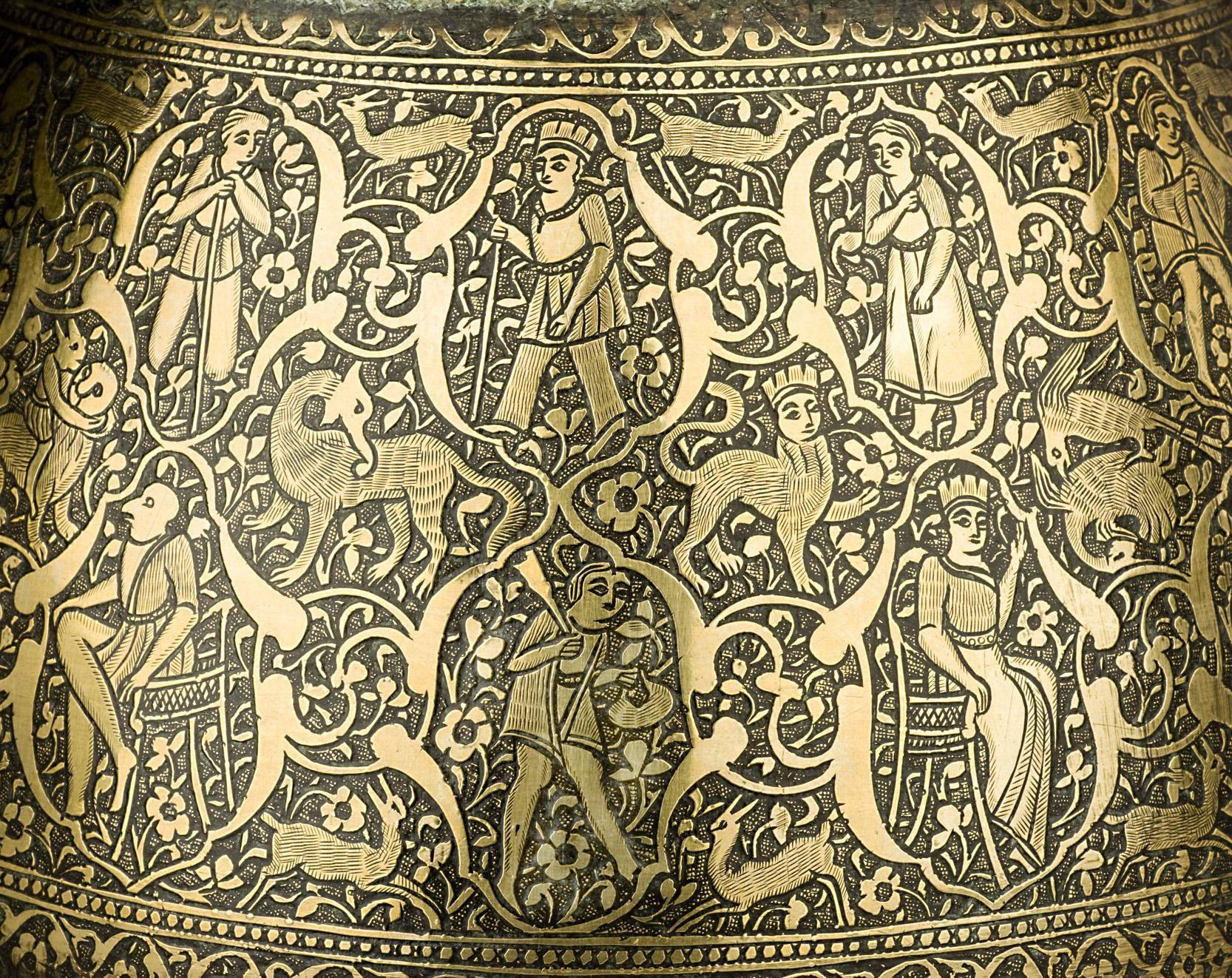 Of curving conical form, with slender neck and flaring mouth, three panels of exterior decoration separated by three ribs. The main body panel densely engraved with acrobats and dancers, gazelles, birds amidst a backdrop of interlacing floral vines.