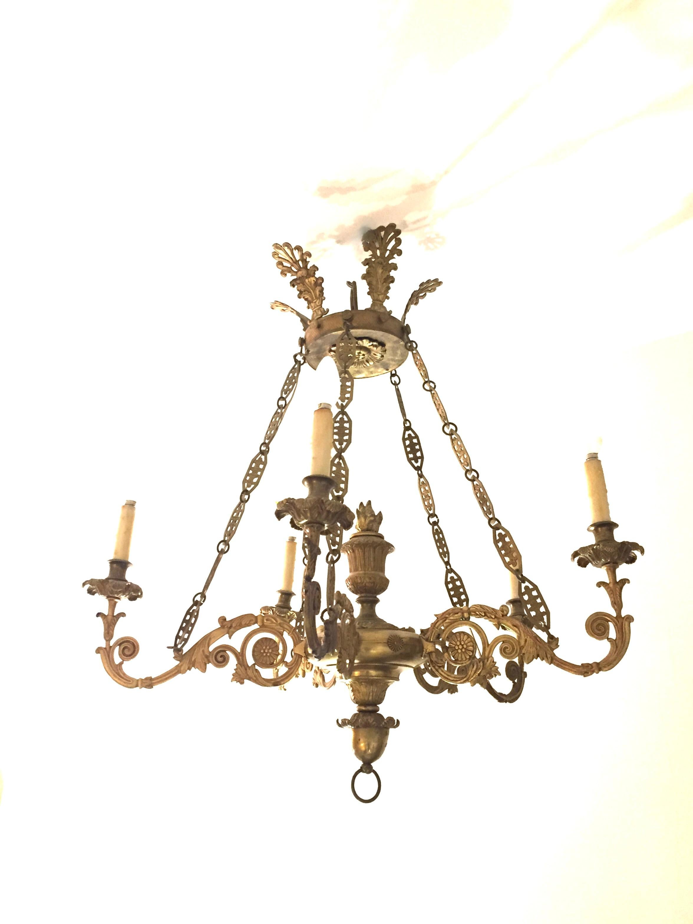 An Original 19th Century Empire bronze chandelier. The piece is beautifully suspended from a palmetto crown by five link chains with a flame center. Five entrenched arms are finished by bronze candle cups and detailed floriate drippers,A heavy
