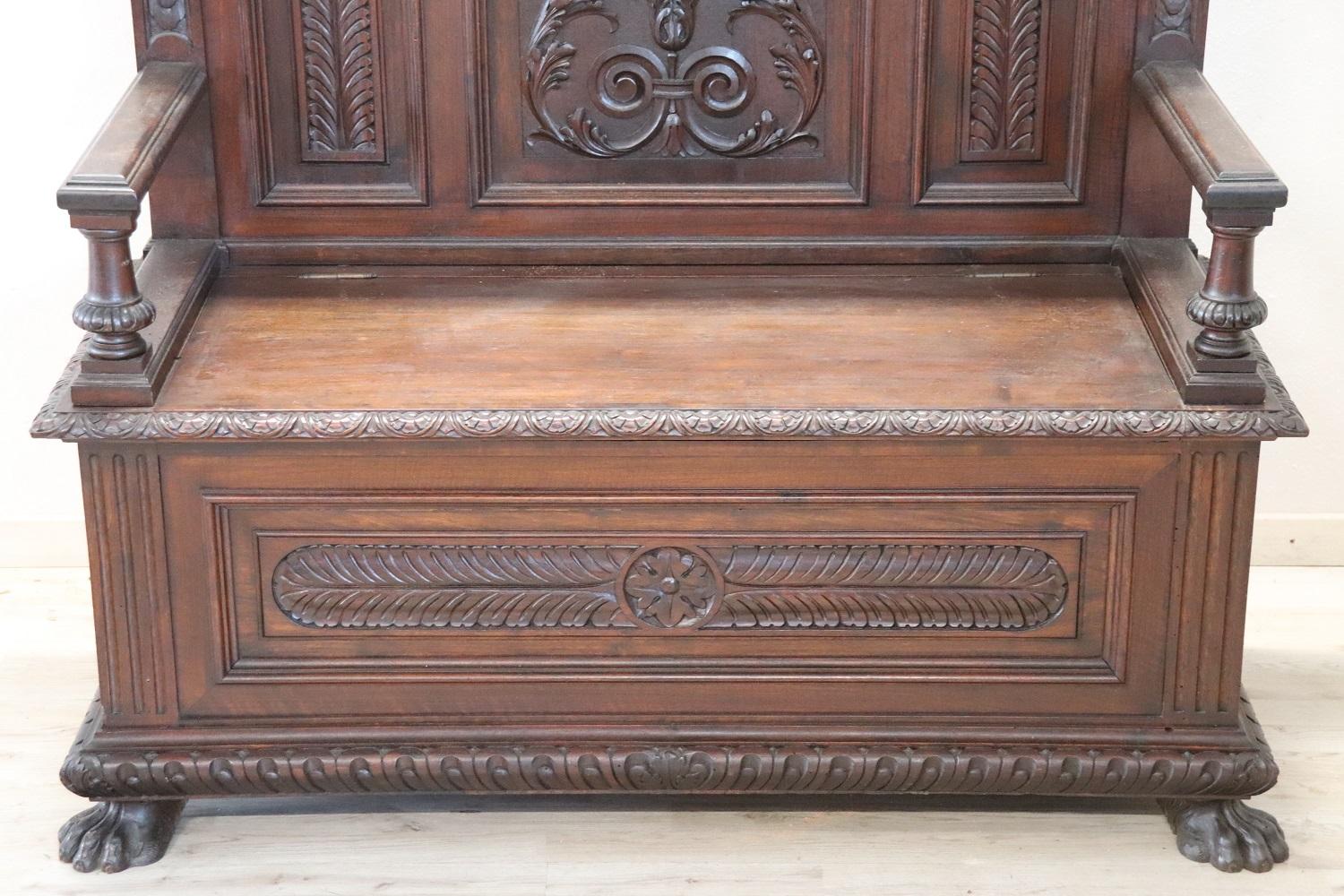 Majestic Italian bench in late 19th century Renaissance style. Made of walnut wood with carved decorations in Renaissance style with grotesque faces. Fantastic big paw feet. High and imposing backrest, the seat rises and inside we find a comfortable