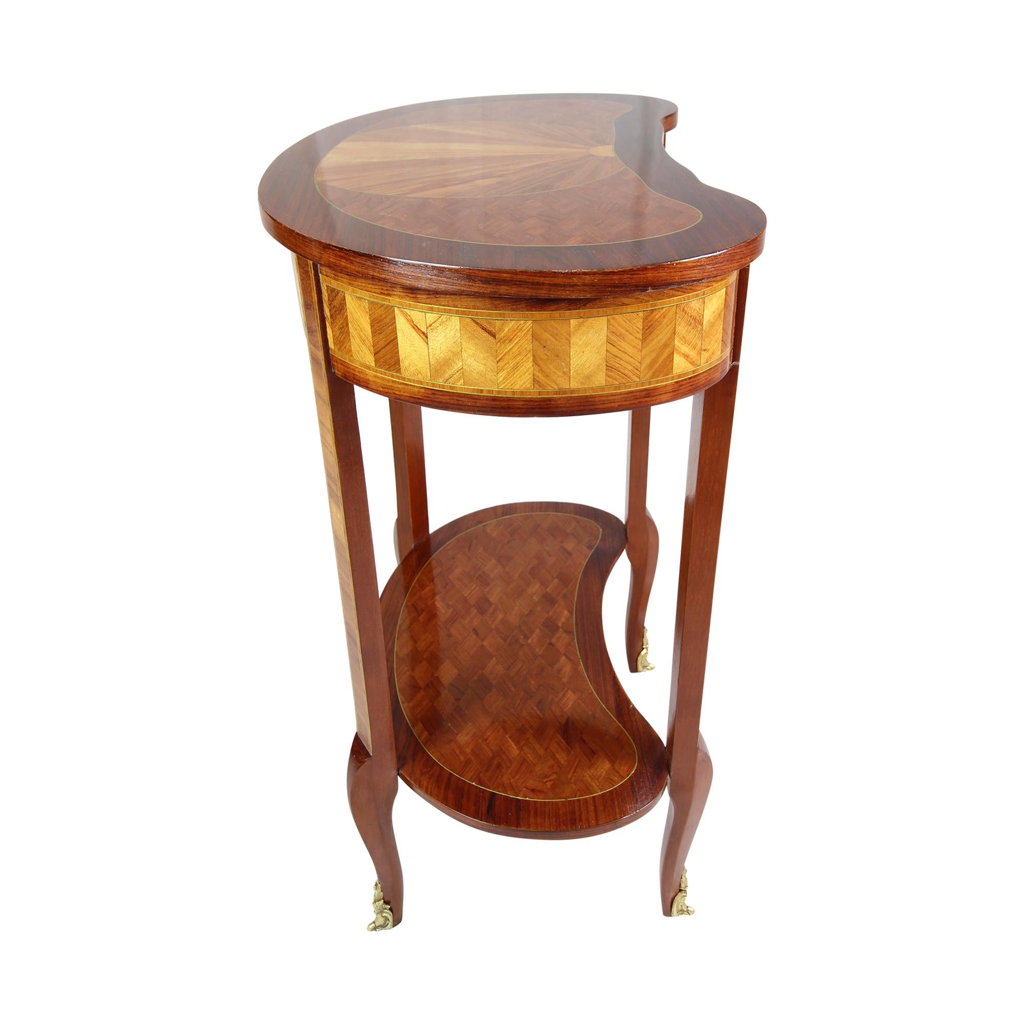 Beautiful side table in kidney shape with intricate marquetry work. The top can be folded up and underneath are three compartments. The top can also be closed. The feet finish with brass ornaments. The Louis XV Style side table comes from France and