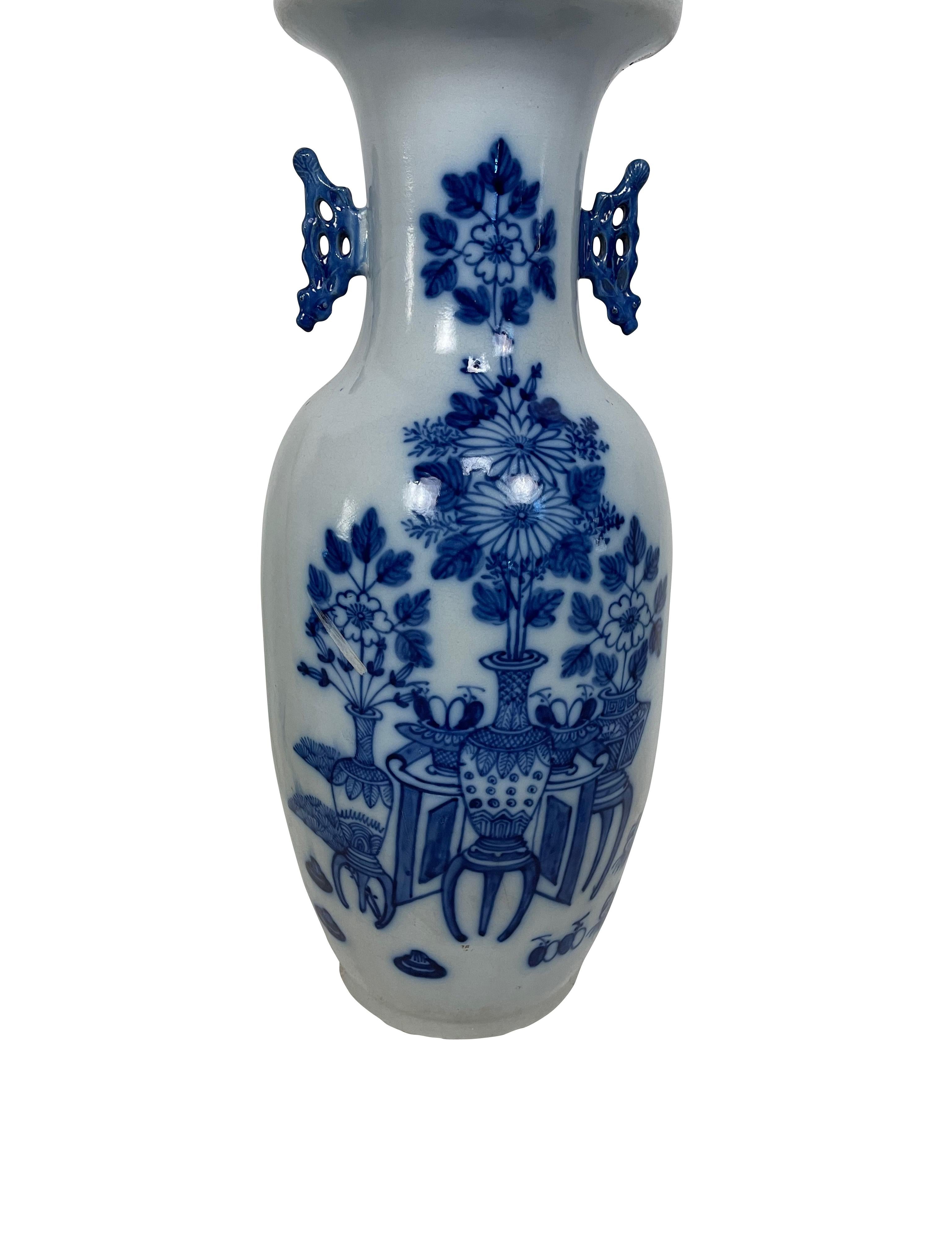 Vase balustre en porcelaine chinoise du XIXe siècle, décoré de fleurs et d'objets divers en bas-relief et en bleu de cobalt sous glaçure sur fond blanc. Le vase a des poignées stylisées moulées en bleu cobalt de chaque côté du large col en entonnoir