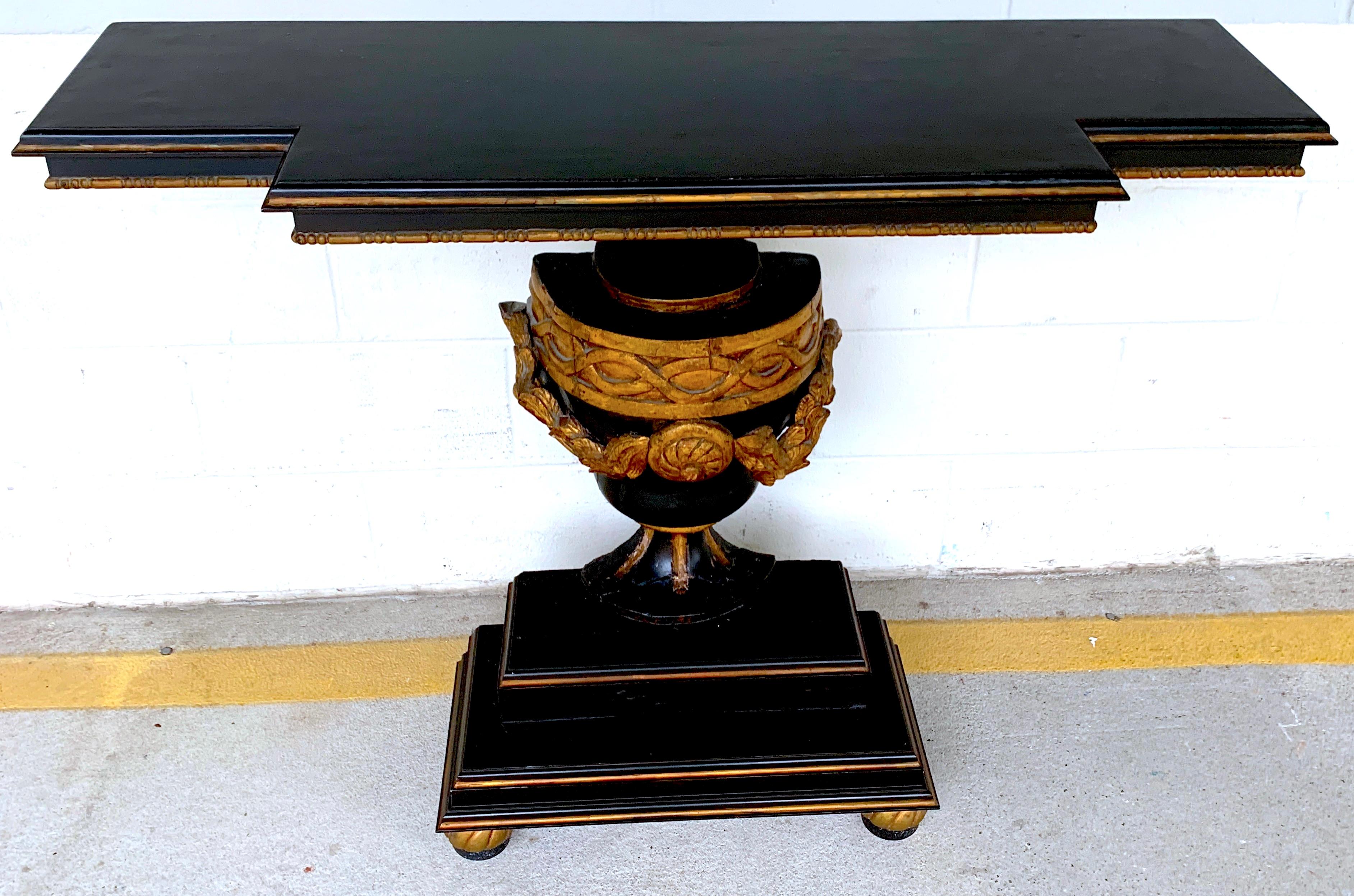 19th continental ebonized and gilt neoclassical carved urn motif console, with canted top with a depth of 10-inches deep at the narrowest and 14-inches deep at the widest, raised on a carved giltwood and ebonized urn motif pedestal base, measuring