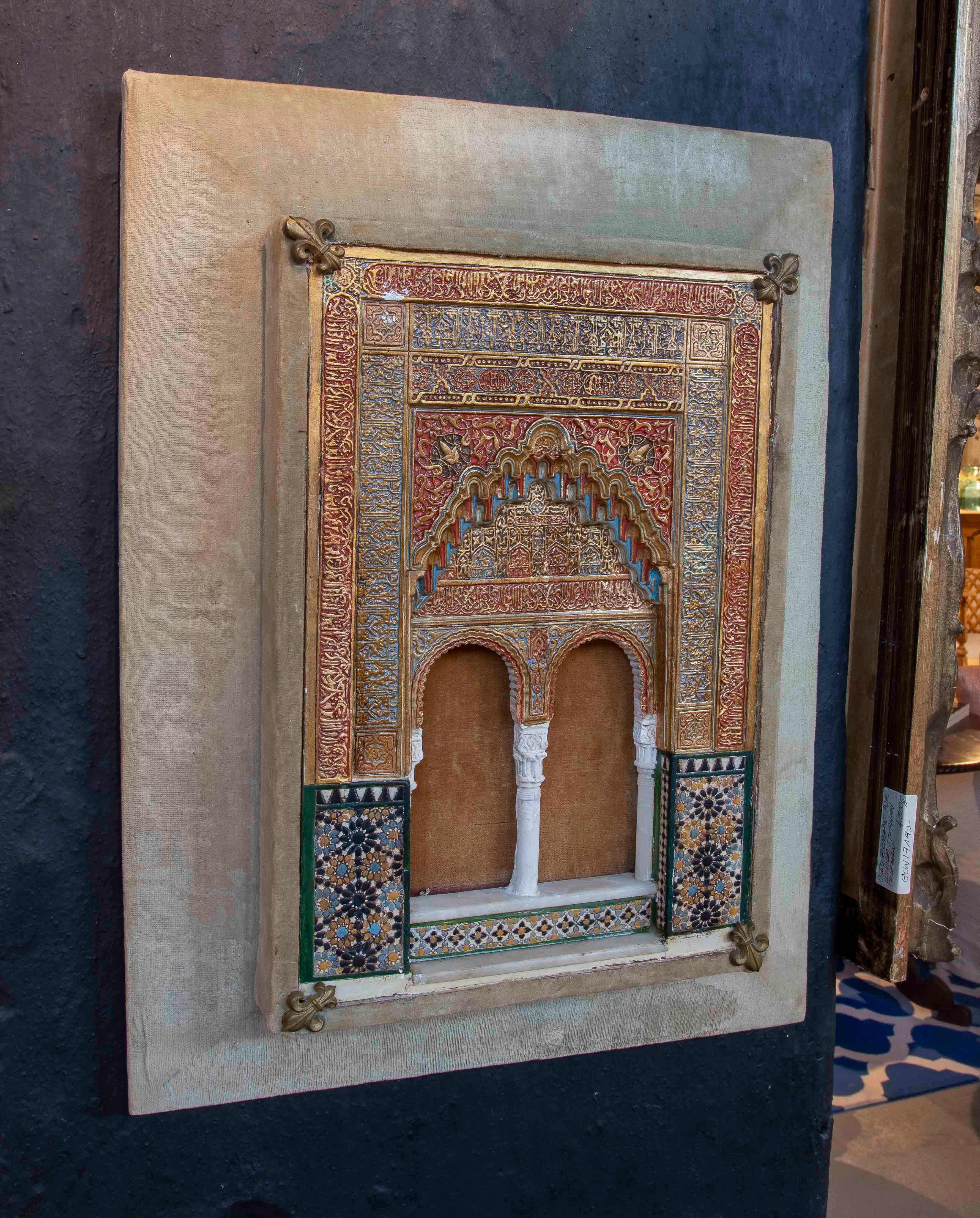 Un exquis modèle mural en relief, finement polychromé et doré, représentant dans les moindres détails un double arc de l'architecture nasride de l'Alhambra de Grenade. Le cadre présente une somptueuse décoration en ataurique et en calligraphie