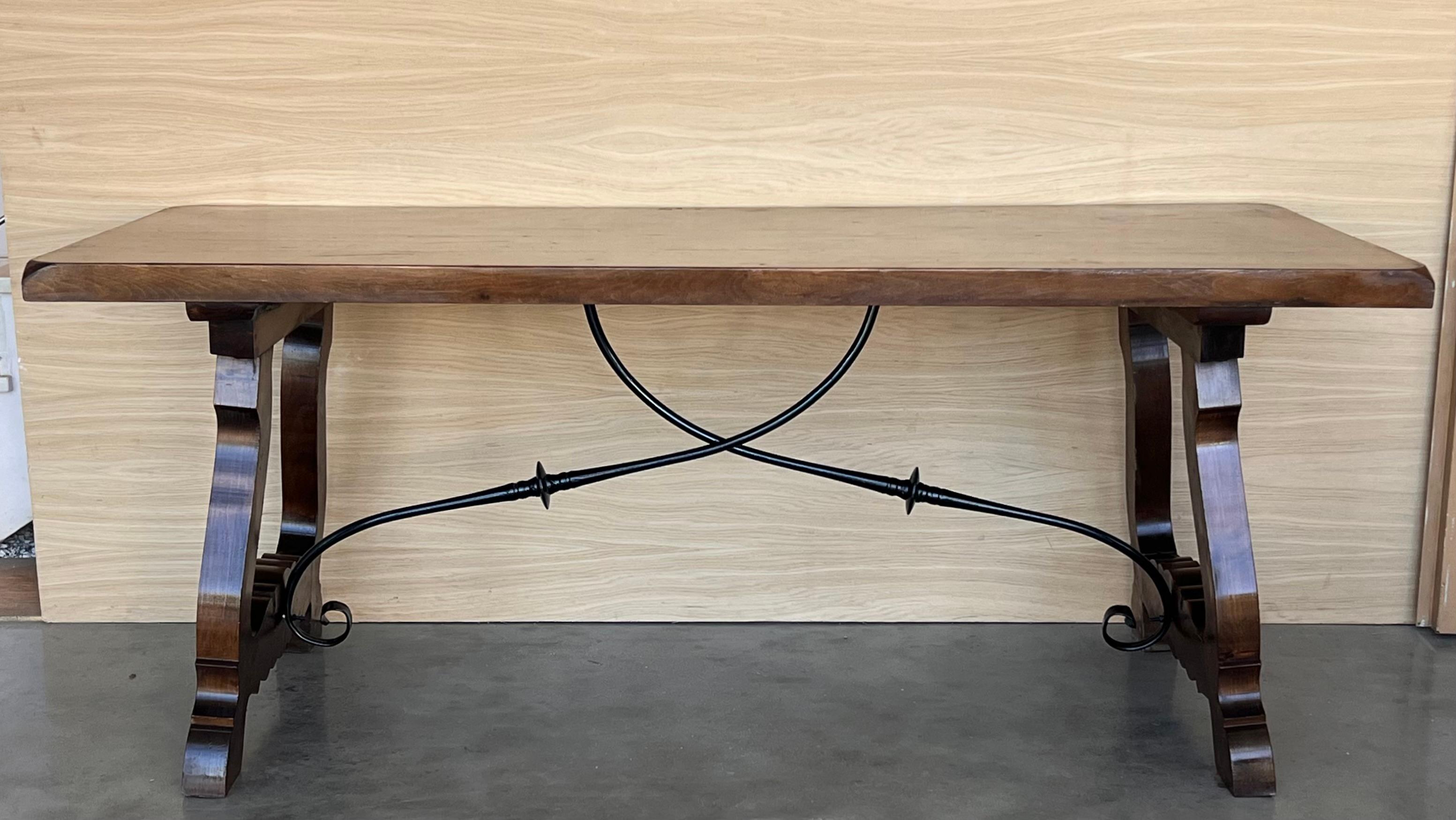 Dining table made of walnut with carved lyre legs and heavy top. 
The lyre legs are very thick.
Beautiful iron stretcher, Spanish, 19th century.