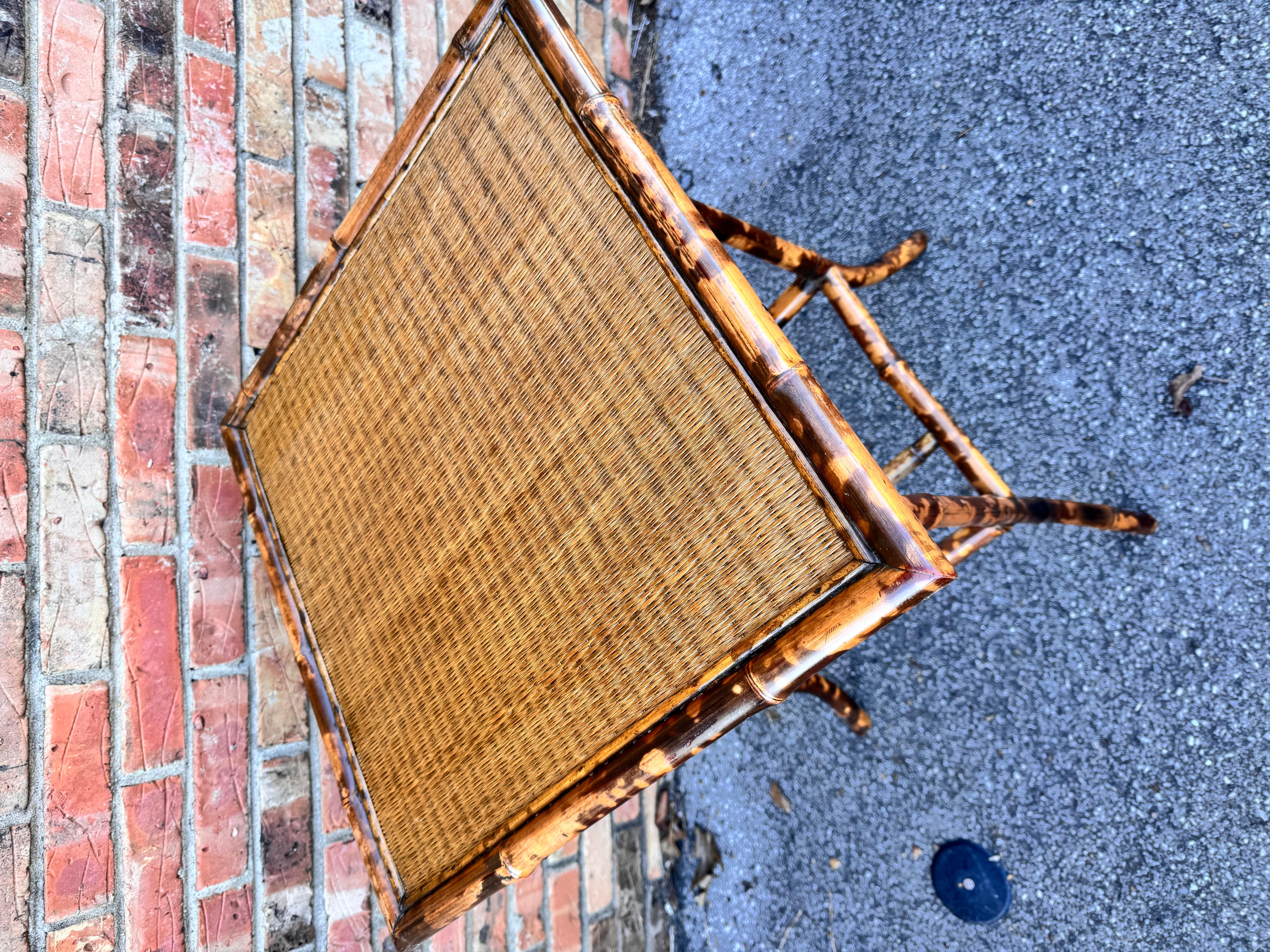 This is a beautiful 19th century English bamboo side table! Tables like these make excellent accent pieces because their color and style is so versatile. The dark hues of the burnt bamboo pair perfectly with the lighter golden of the rattan top and