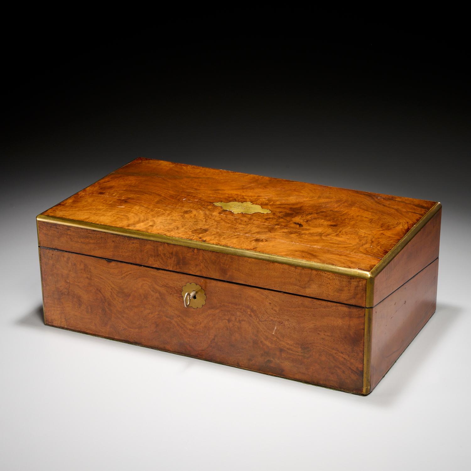 19th c., England, a figured mahogany lap desk banded in brass to protect a piece that was in regular use and likely travelled with the owner.

The hinged top opens to a gilt tooled leather writing surface and fitted storage compartments. The fitted