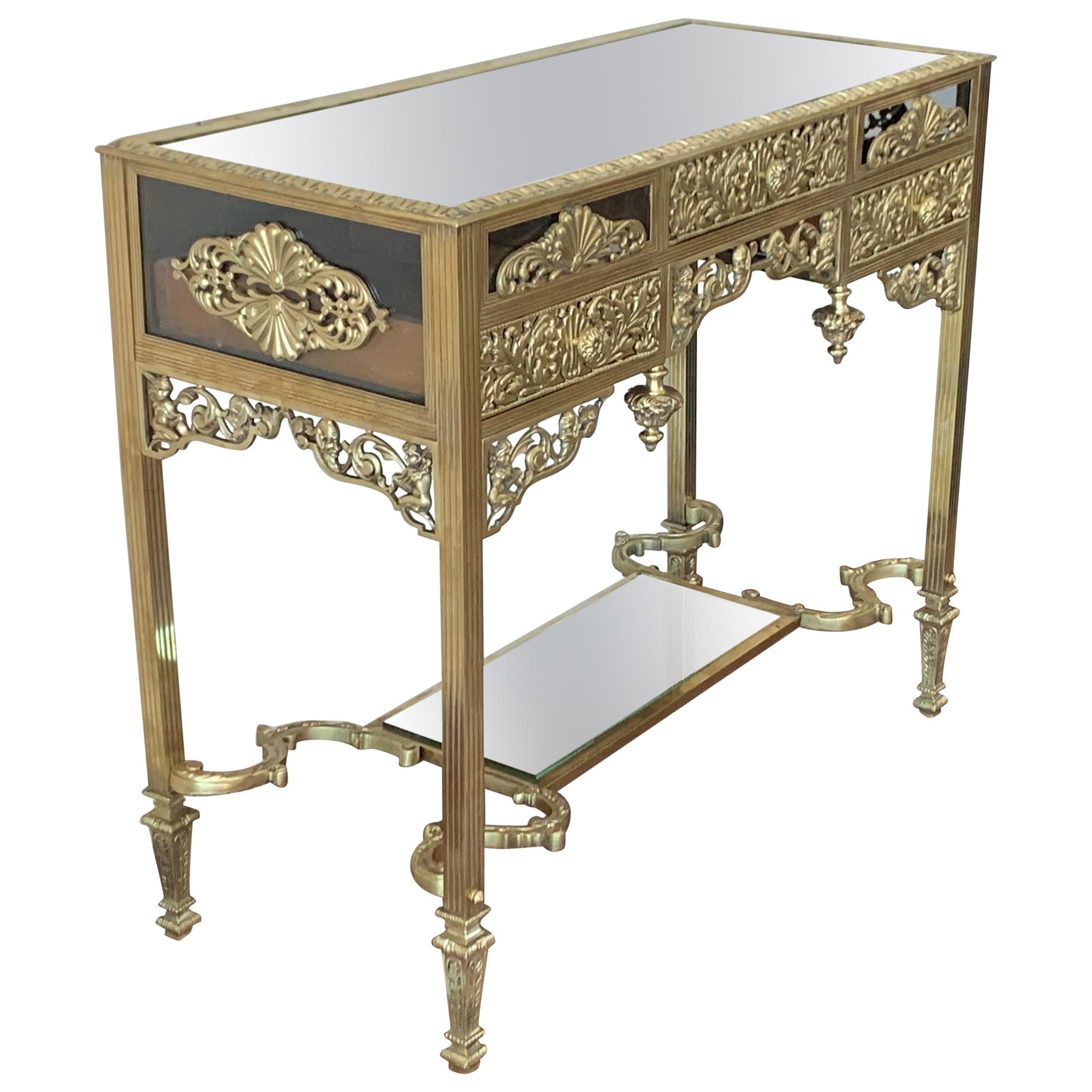 The rectangular top with rounded corners and a mirror top, mounted with an oval foliate decorated swivel bronze surmounted by a floral wreath and ribbon knot, raised on reeded legs joined by an interlaced stretcher and ending in toupie feet.