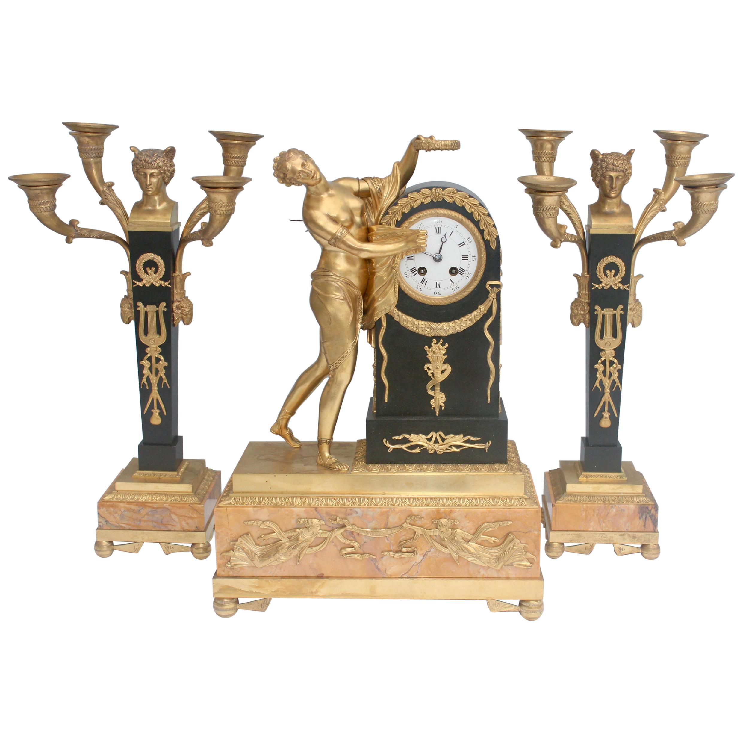 A mid-19th French ormolu and patinated bronze three-piece Clock Garniture 
Composed a green patinated, chiseled and gilt bronze Mantel clock and a matching pair of four-lights candelabras, 
The clock representing Psyché with the time unveiled, the