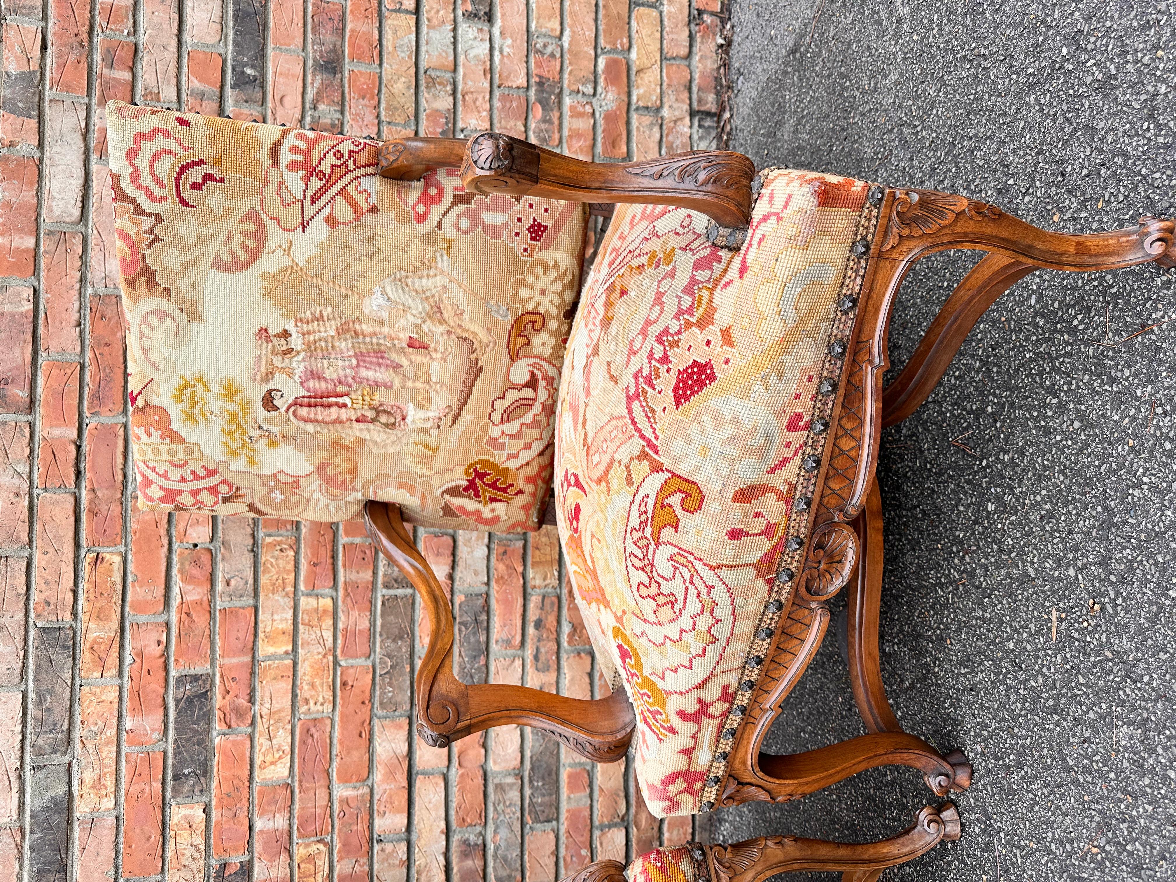 This is a beautiful pair of antique needle point chairs! They have been adorned in in hues in peach, beige and rust tones and pair wonderfully with the warm wood. The arms and legs have stunning hand carved designs that are immediately eye-catching.