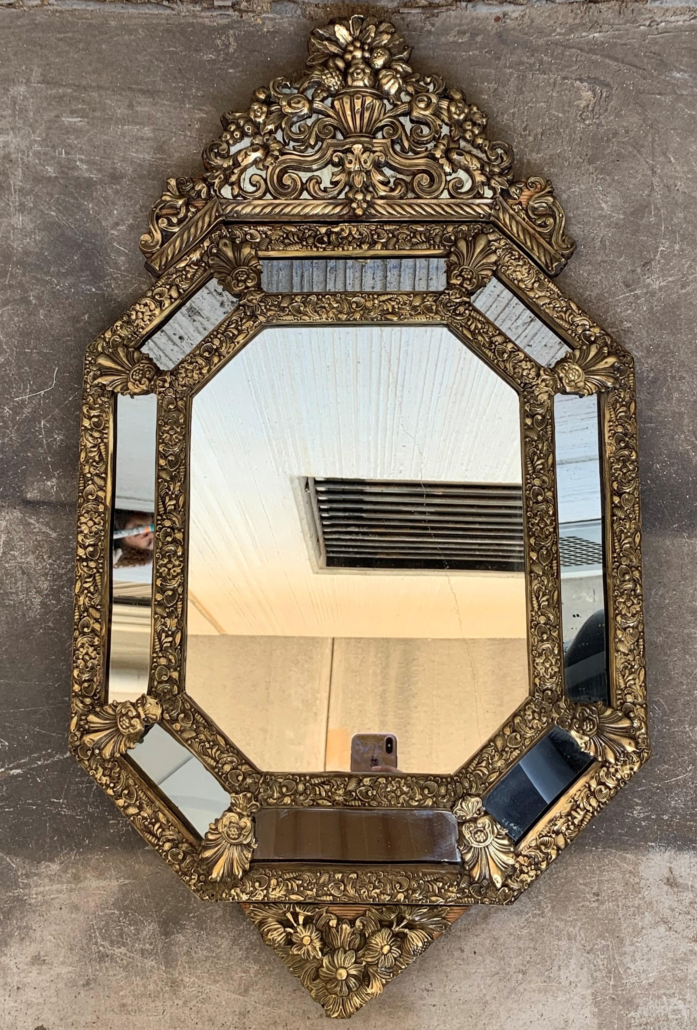 19th century French repousse hexagonal brass relief wall mirror with crest
An elegant Napoleon III period mirror made with central beveled glass and eight rectangular glasses joined between them by decorative brass repousse floral patterns.
This