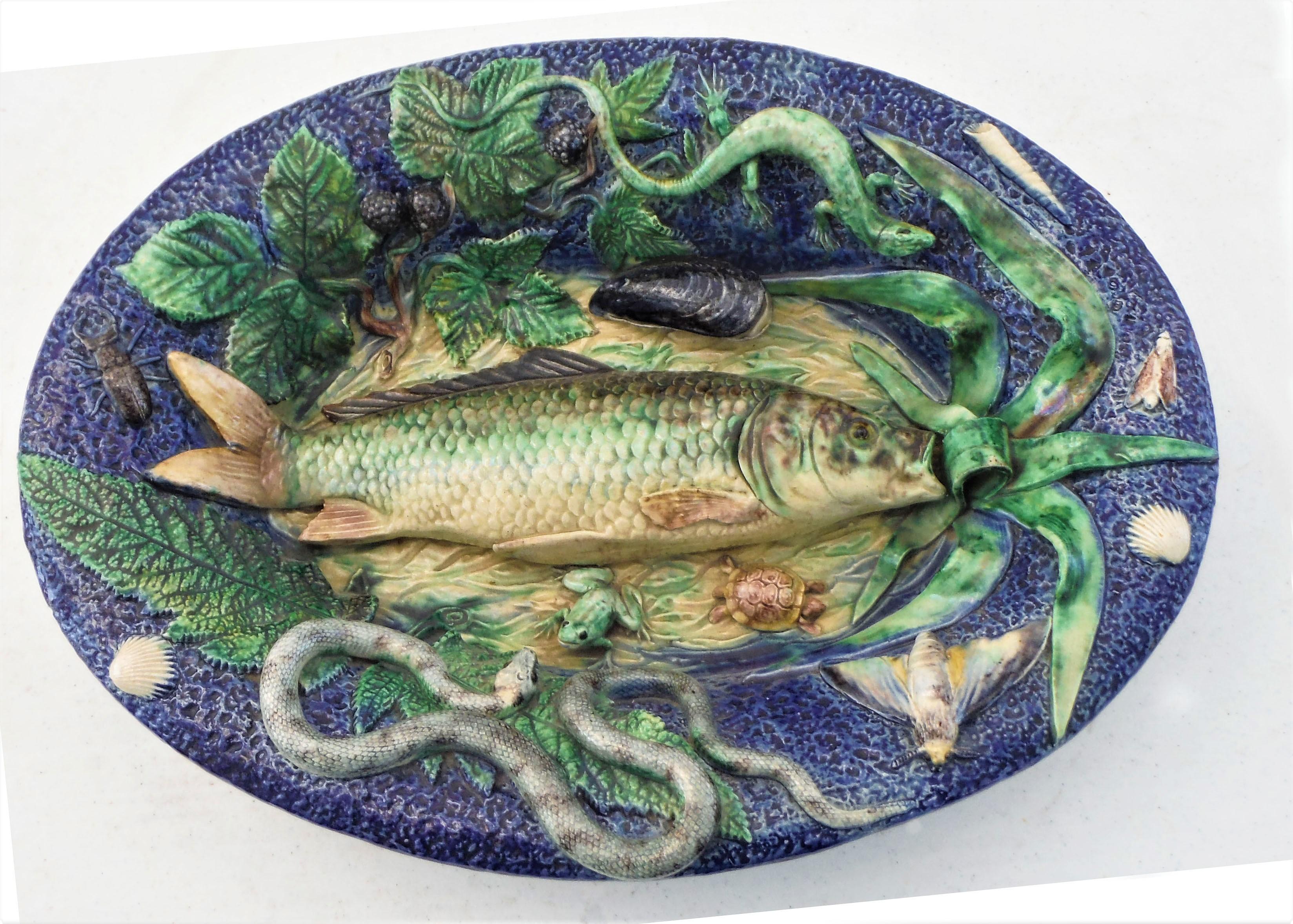 A large Palissy fish platter in a basin form from the School of Paris, circa 1875 with a large fish on the center surrounded by a lizard, a turtle, a frog, a snake, some bugs, shells, a large mussel, green leaves and blackberries.
Attribution to