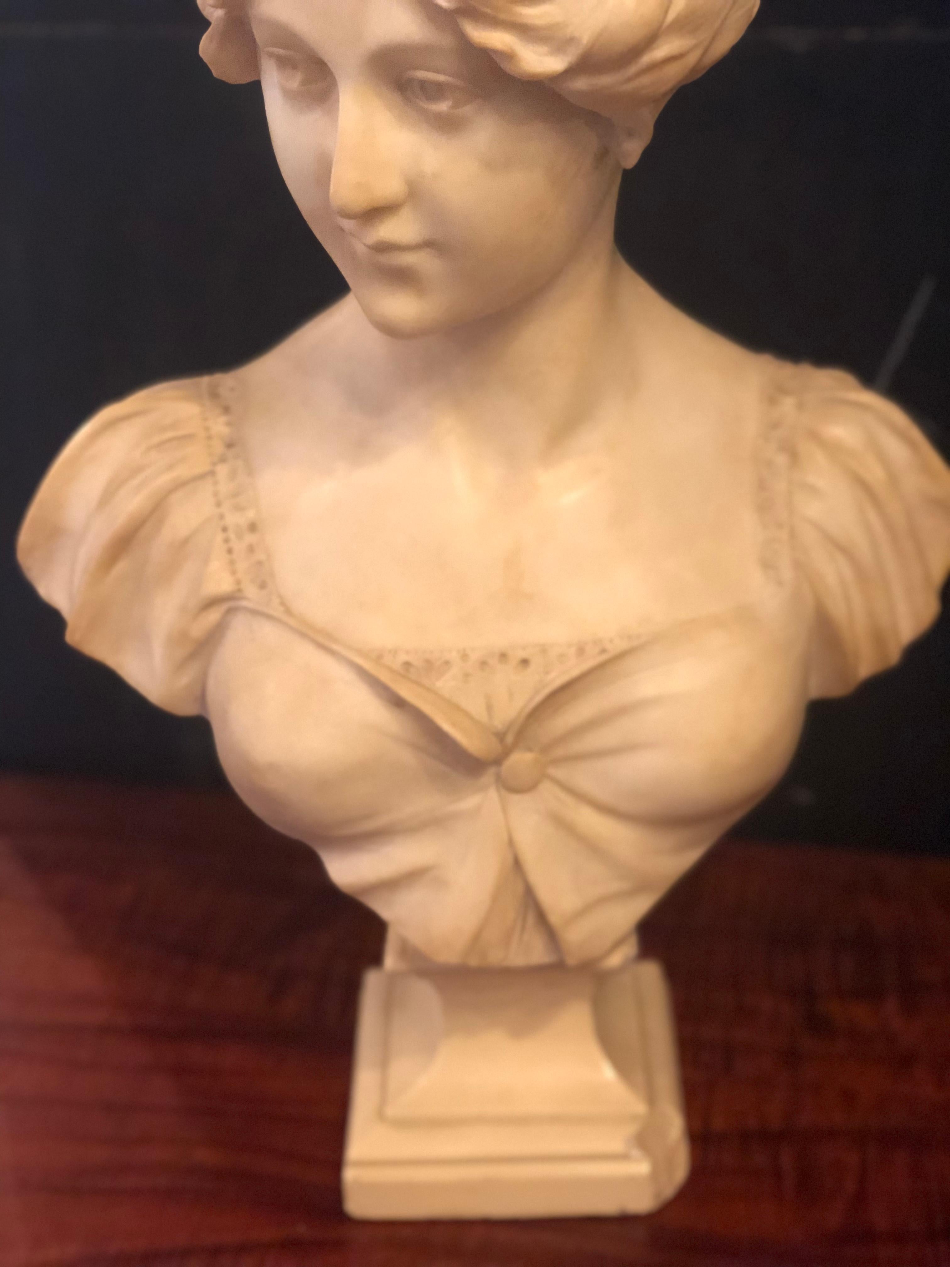 19th or early 20th century marble bust of a young woman signed on reverse. This young beauty having her hair in a bun with a rose on the side is in full Victorian dress.