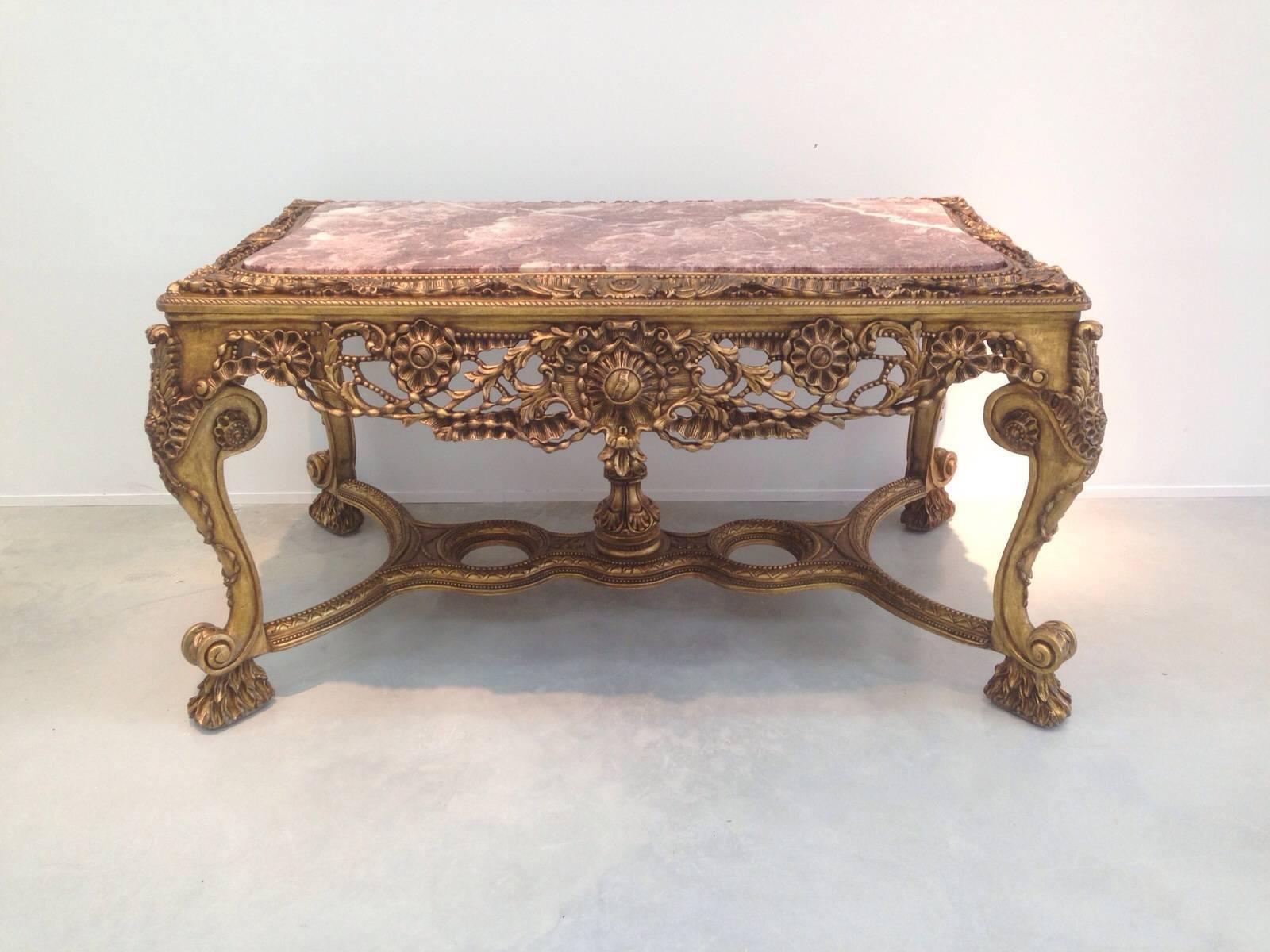 The table has a wonderful contrast between the brilliant gold carvings, rizh reddish wood finish, and pink stone.