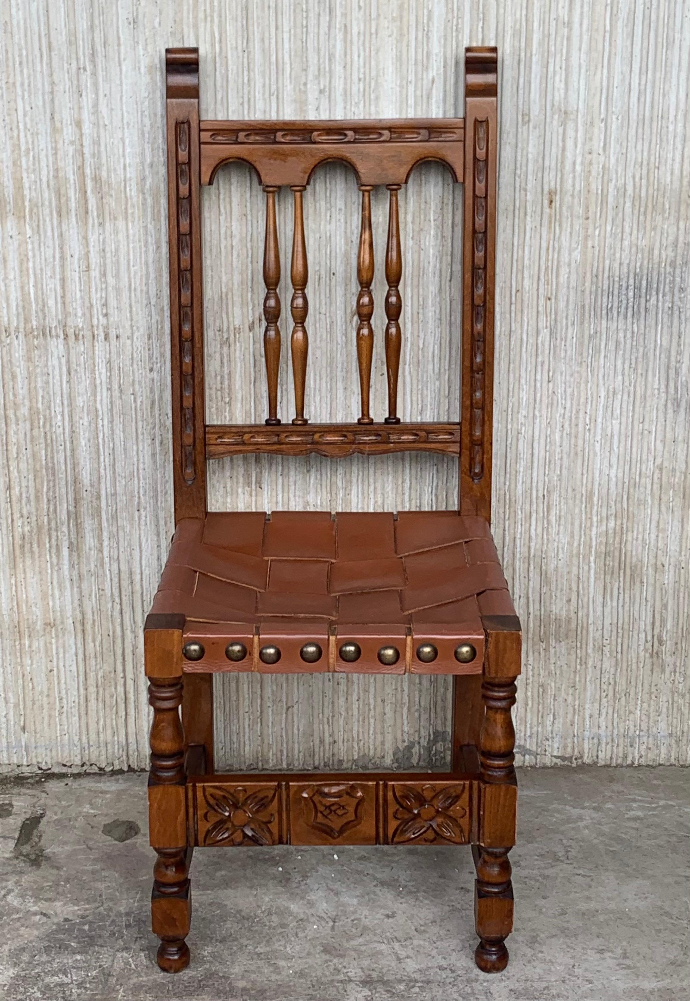 A set of 4 Spanish chairs with leather sling seatsand backs on oak and sycamore frames with hand carved decoration. These chairs are true to the Spanish character and each features carvings that employ typical Spanish elements. The leather sling