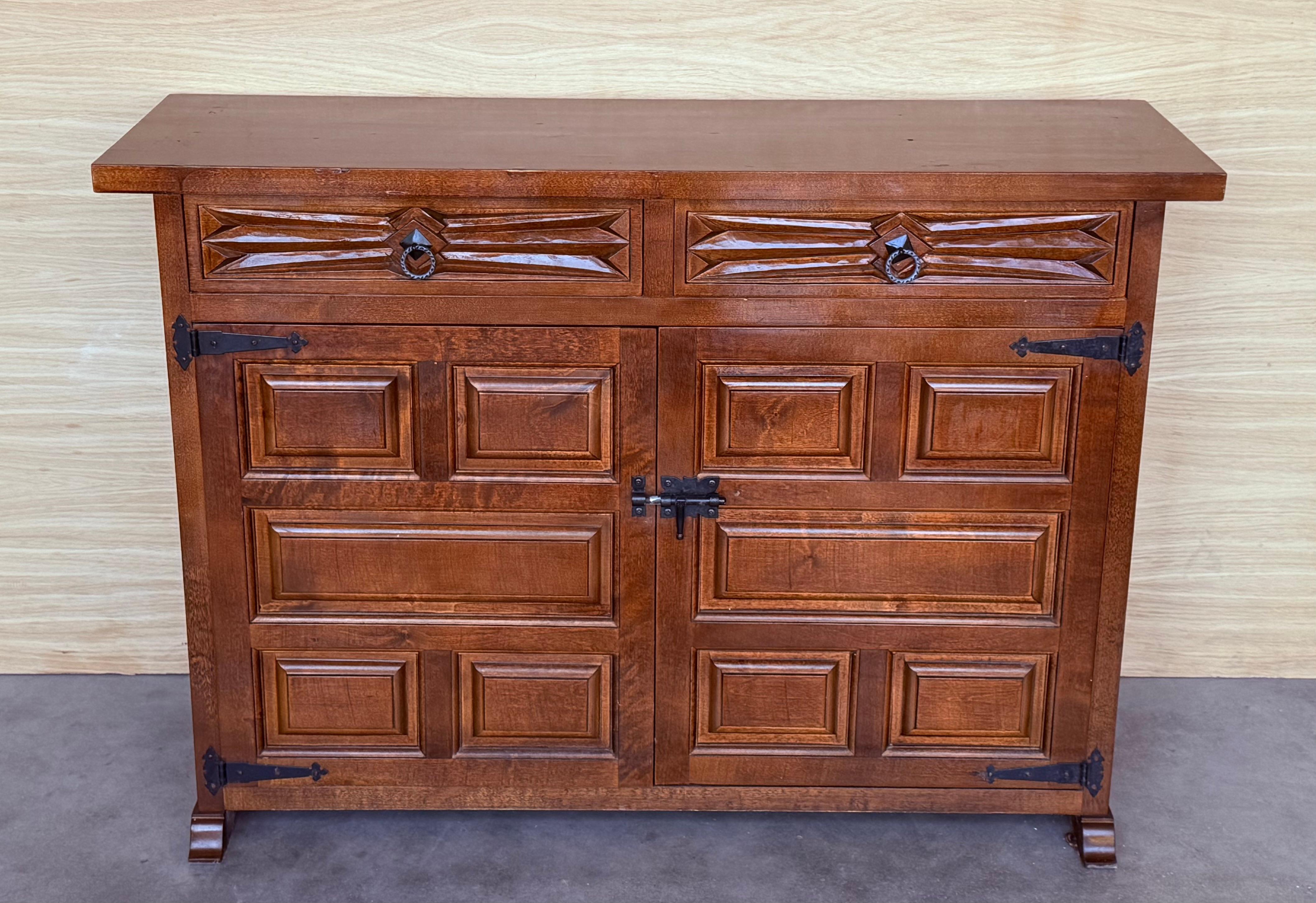 From Northern Spain, constructed of solid walnut, the rectangular top with molded edge atop a conforming case housing two drawers over two doors, the doors paneled with solid walnut, raised on a plinth base.
Beautiful carved drawers and original