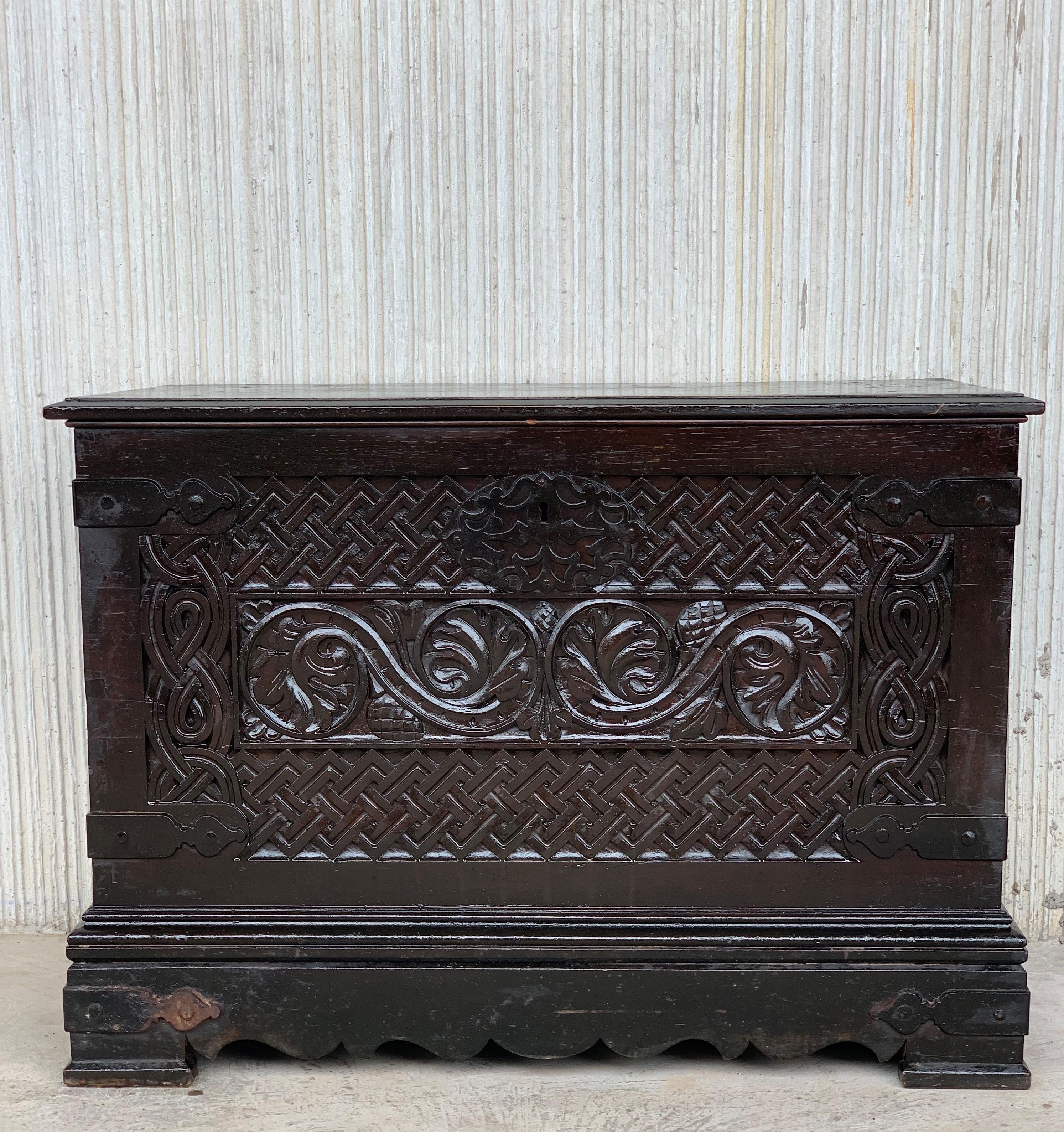 Having a hinged top and raised on shaped bracket feet, 19th Spanish Baroque Walnut Trunk with Handcarved Decoration with two large brass carrying handles on sides, retaining antique lock