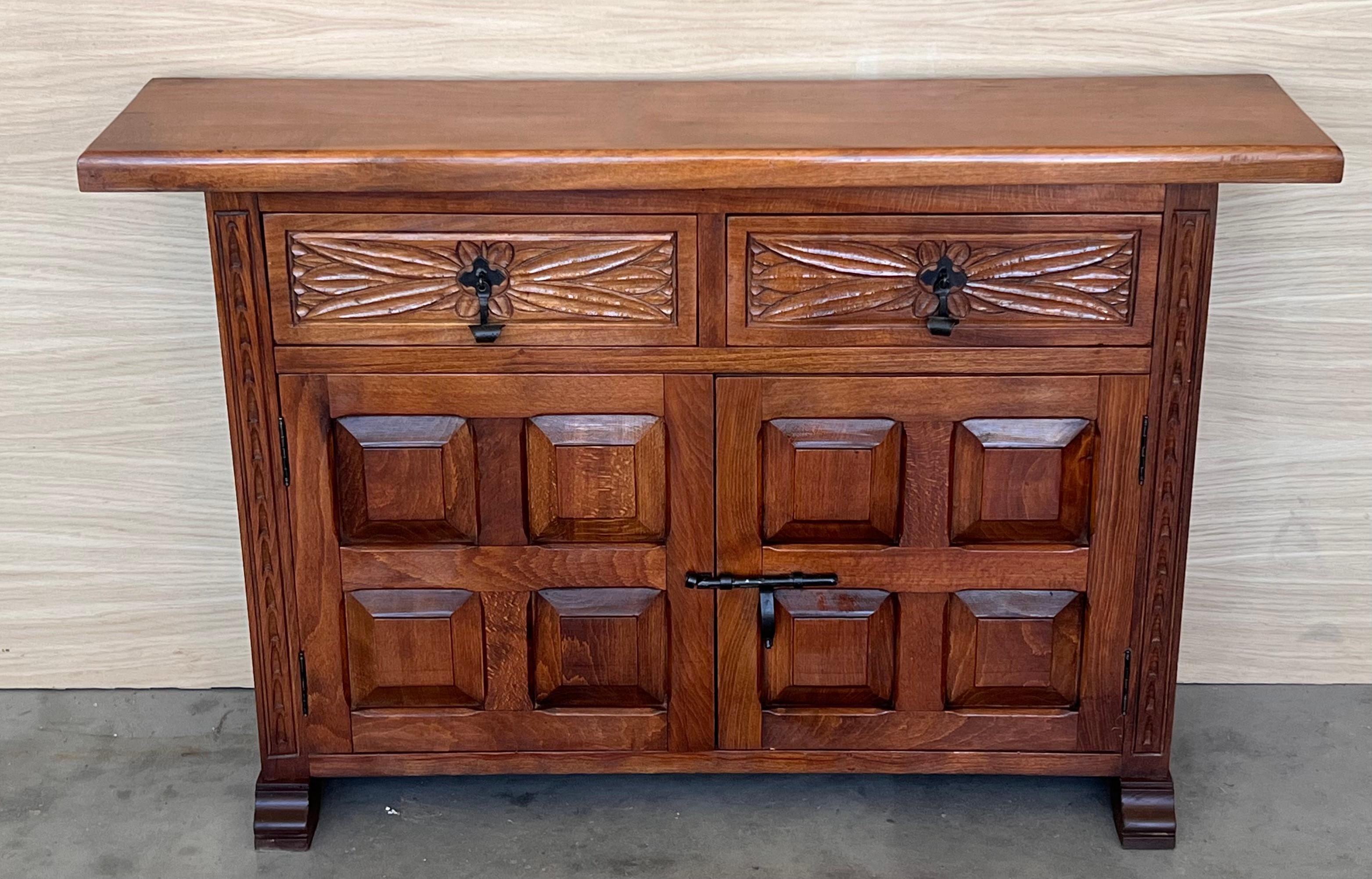 From Northern Spain, constructed of solid walnut, the rectangular top with molded edge atop a conforming case housing two drawers over two doors, the doors paneled with solid walnut, raised on a plinth base.
Beautiful carved drawers and original