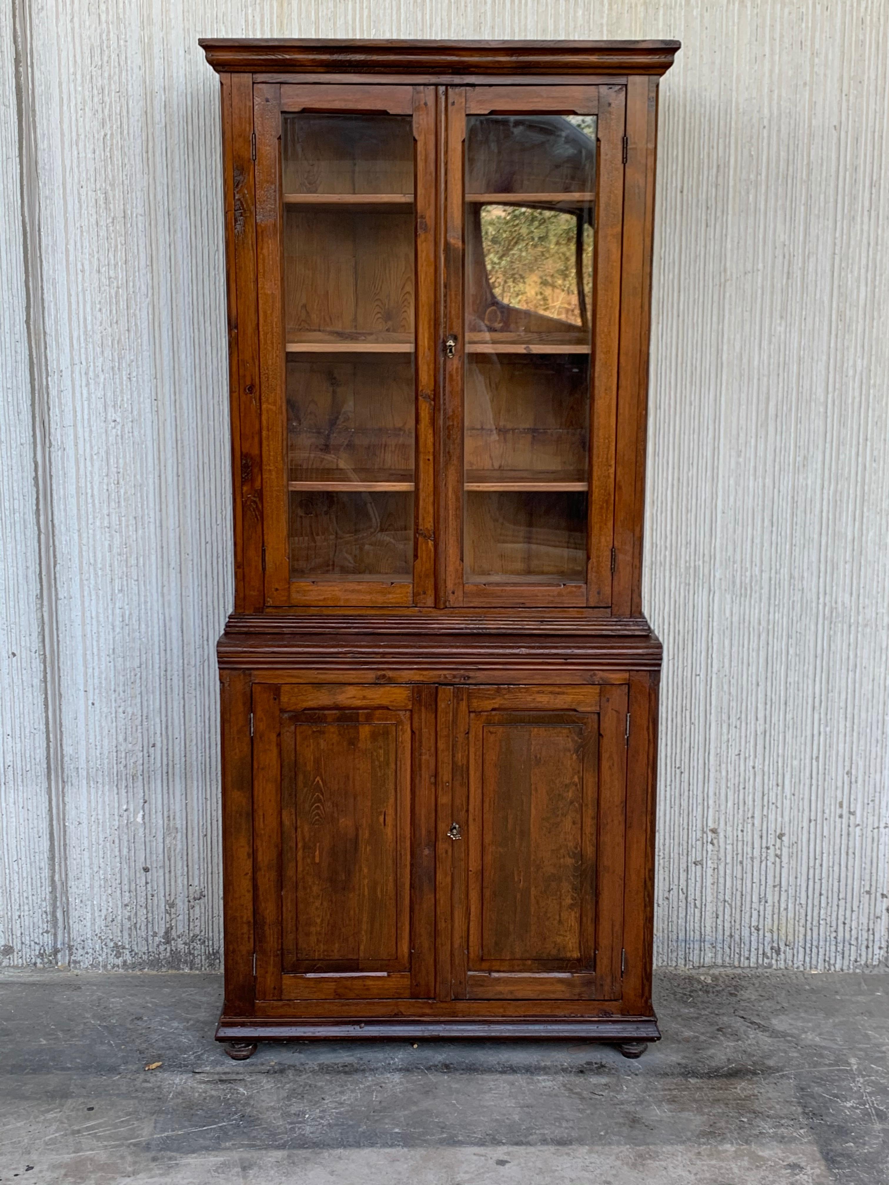 Absolutely gorgeous vitrine cabinet from Spain. In two parts. Originally used as a bookcase. Stunning patina, with its warm pale golden/brown. Paned glass cabinet doors above, and handsome profiled doors in the bottom part. Very suitable for many