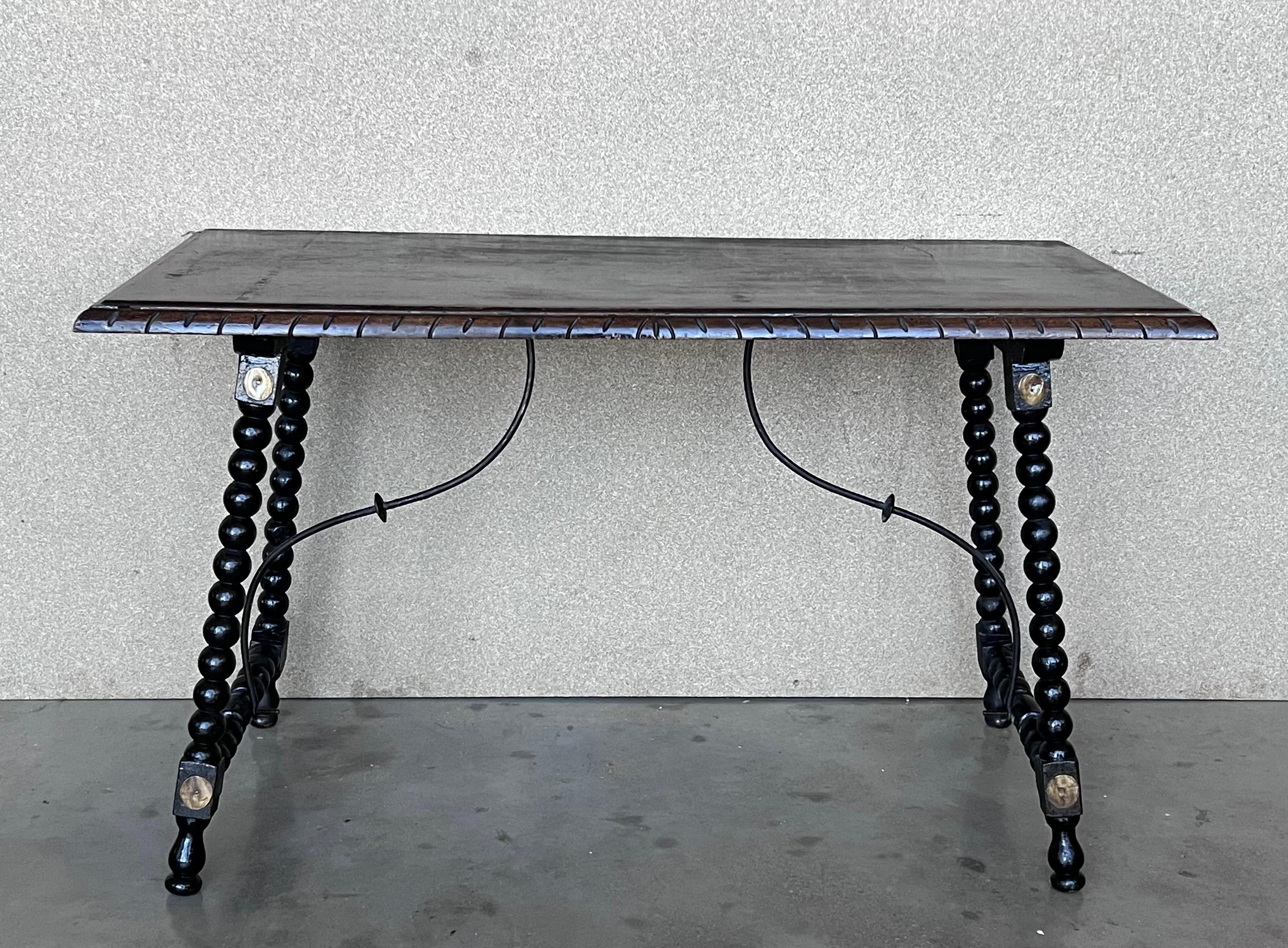 Side table of walnut with turned legs and beleveled top. Spanish, the legs are connected by an original iron stretcher, 19th century.
The frontal legs are embellished with a gold metal plates.