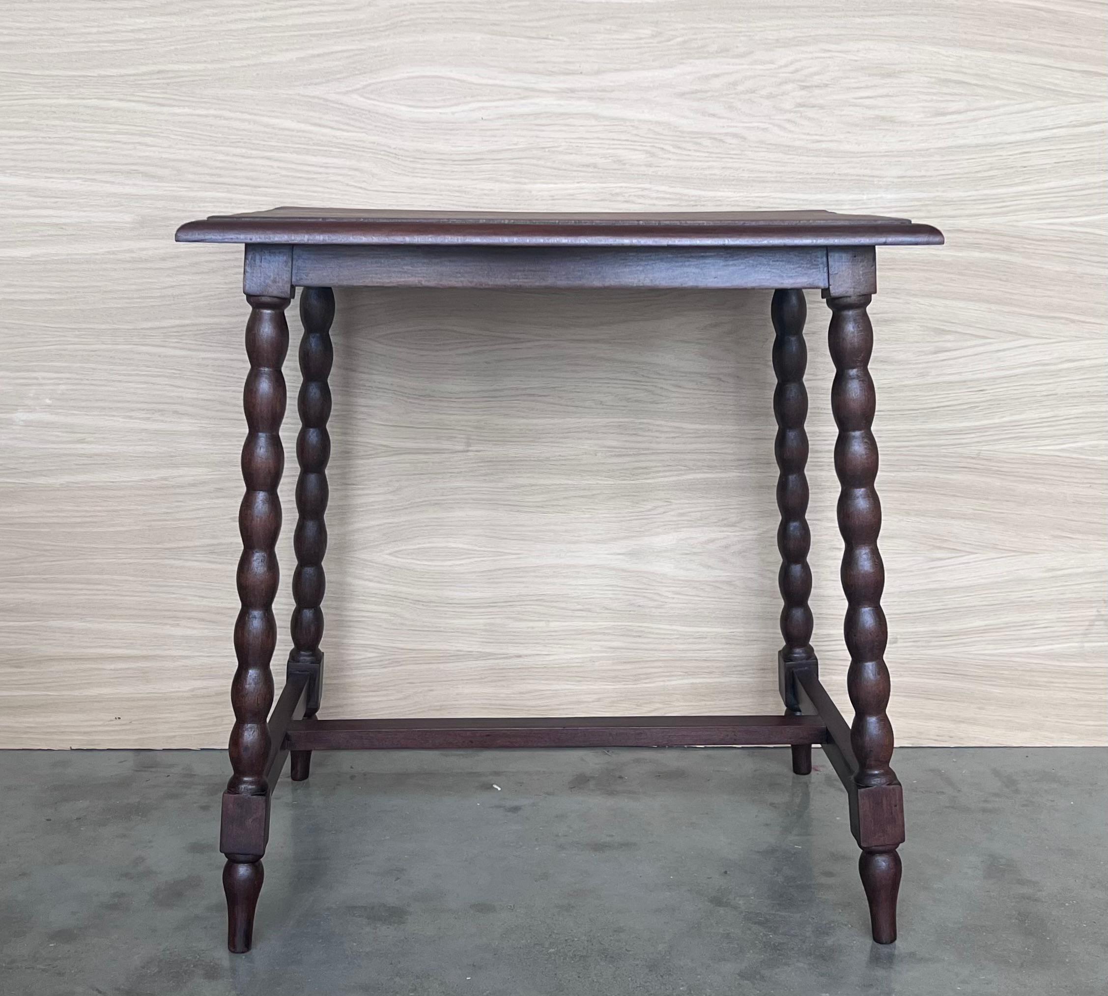 Side table of walnut with turned legs and beleveled top. Spanish, the legs are connected by an original iron stretcher, 19th century.
