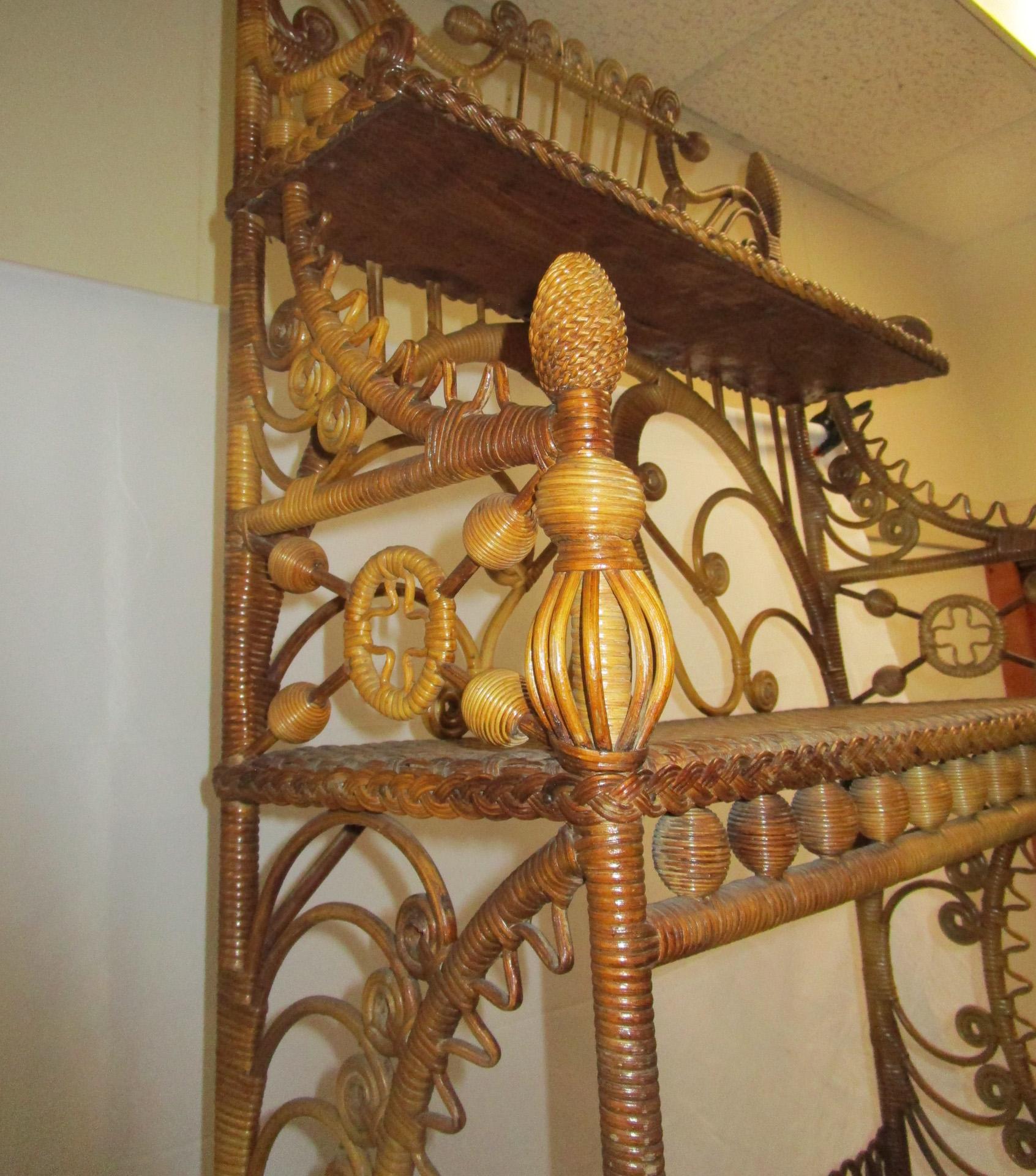 From the premiere American wicker manufacturing firm of Heywood Brothers & Co., Gardner, Massachusetts, this fantastic natural wicker Étagère has all the bells and whistles of Victorian excess. With its spools, curlicues, scallops, wooden balls,