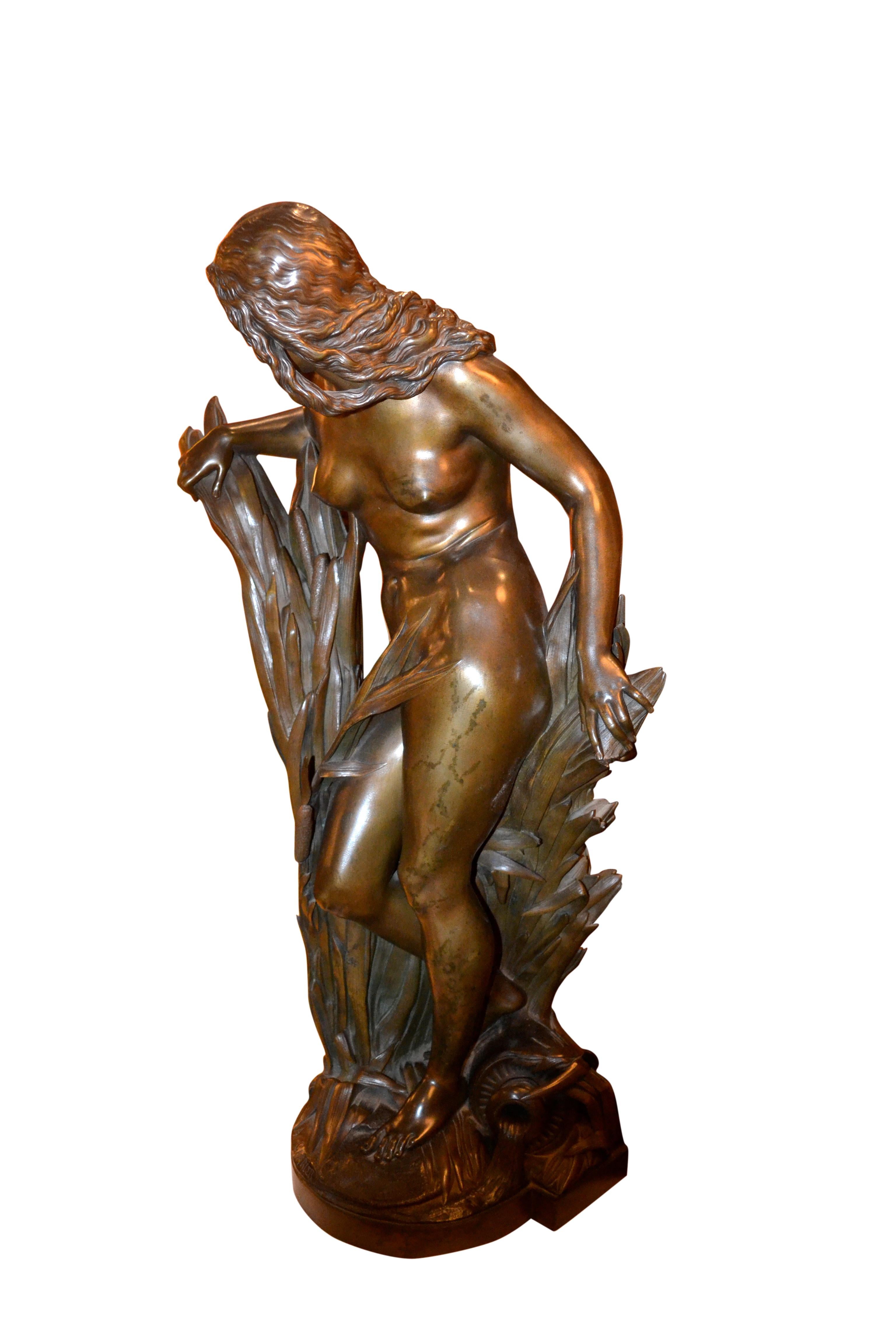 A very fine cast and chased bronze showing a beautiful standing nude nymph, parting and emerging from between tall bull rushes at the edge of a stream. At her feet is a water jug. The bronze is signed A. Carrier with the 