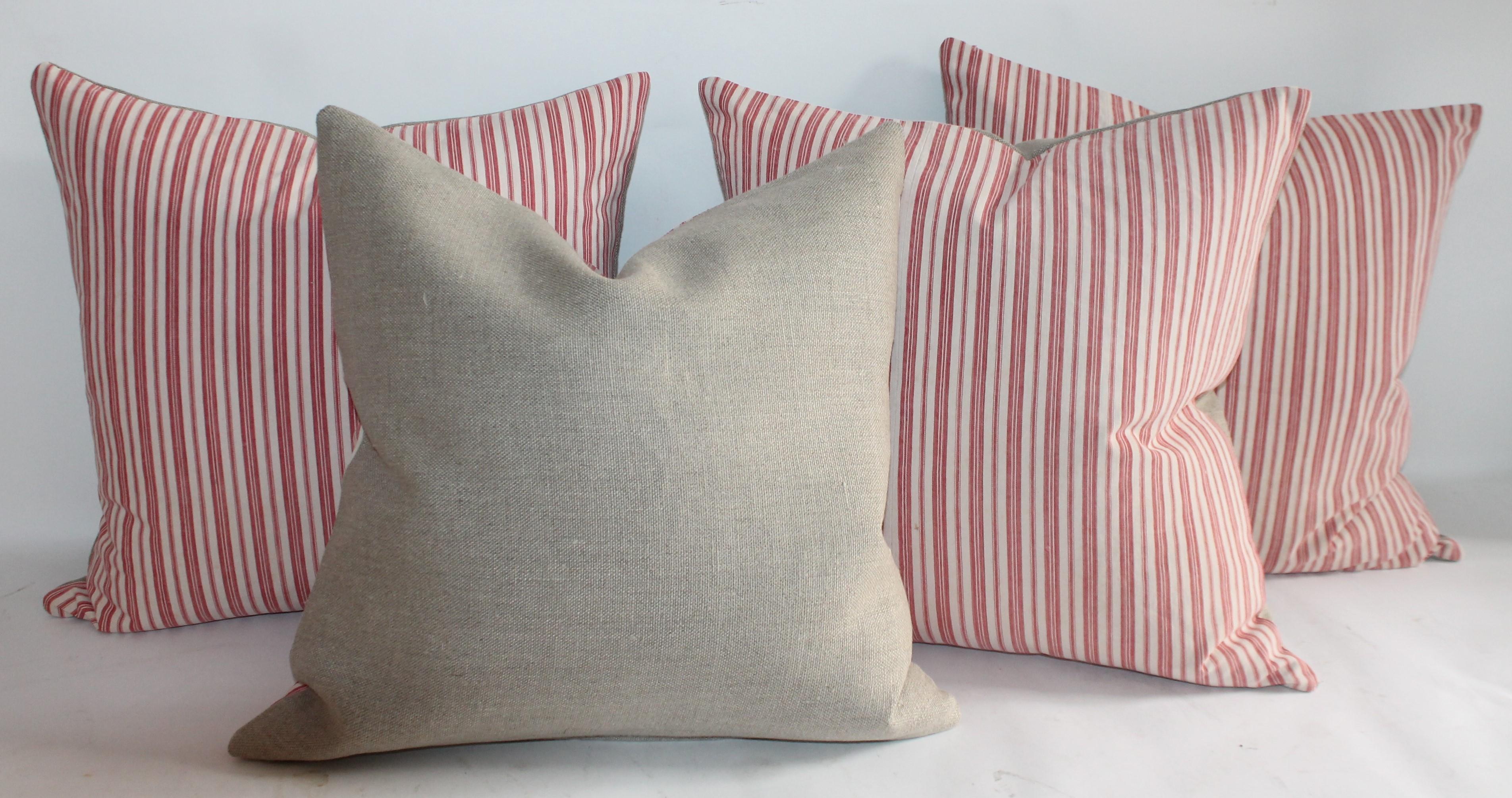 19Th century red and white ticking pillows with beige cotton linen backings. The inserts are down and feather fill.
