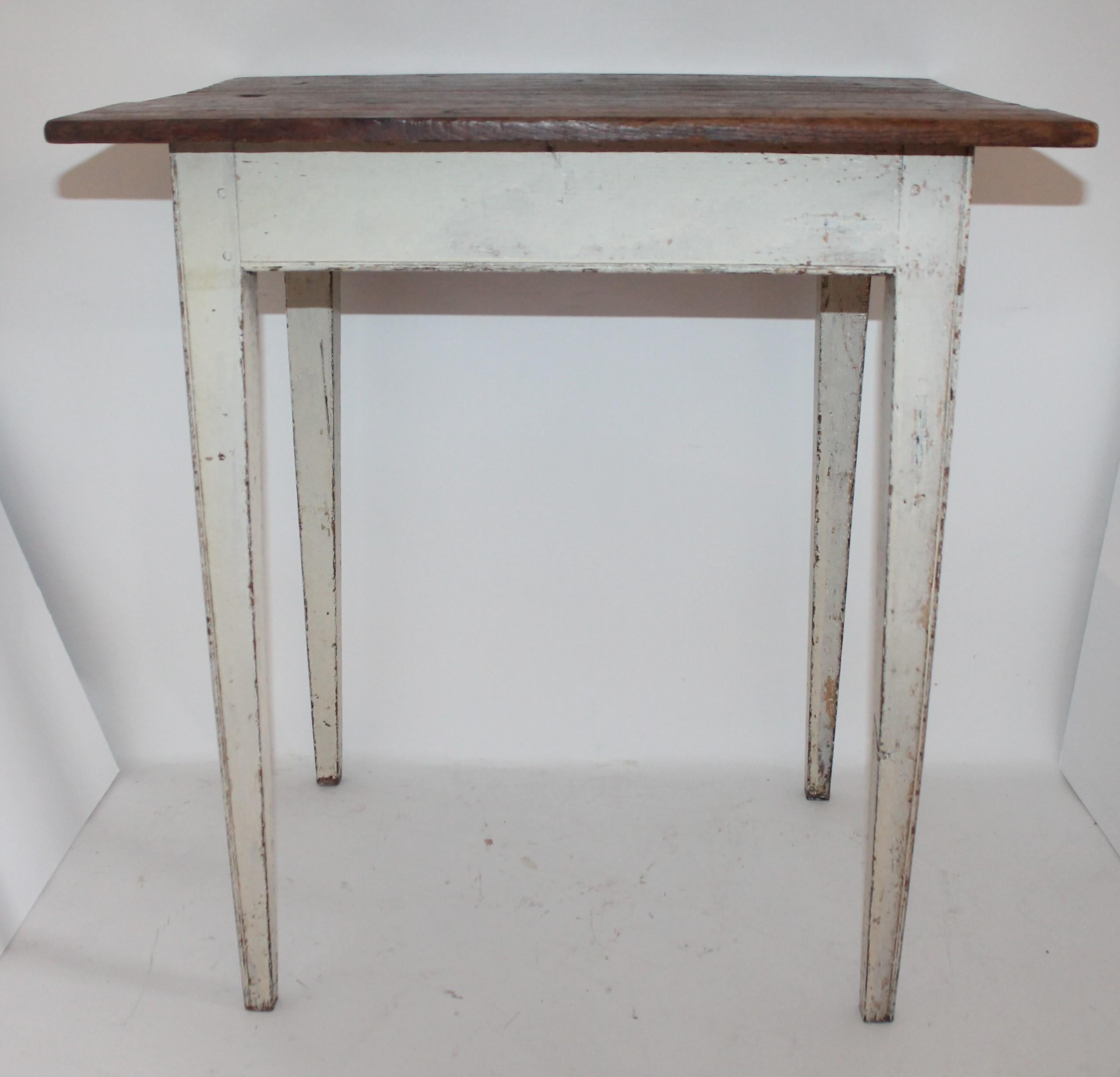 This folky country original white painted taper leg side table is in good and sturdy condition. This three board top is a scrub top and in walnut wood.