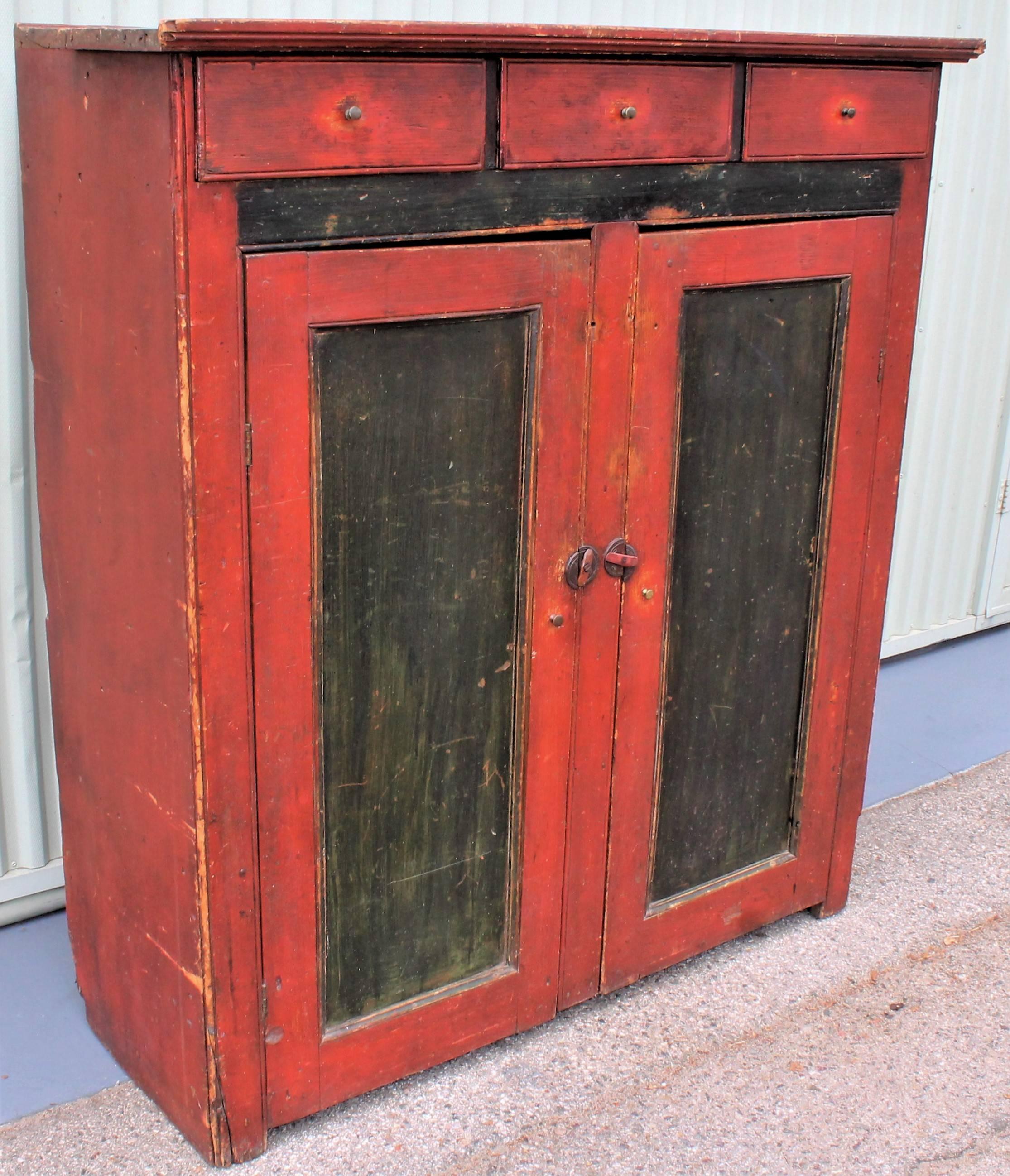 Original black and red painted three-drawer over two doors jelly cupboard from Vermont. This all original painted cupboard is in great condition and retains all original hardware. Special Fine small brass pulls on the dovetailed drawers. Early wood