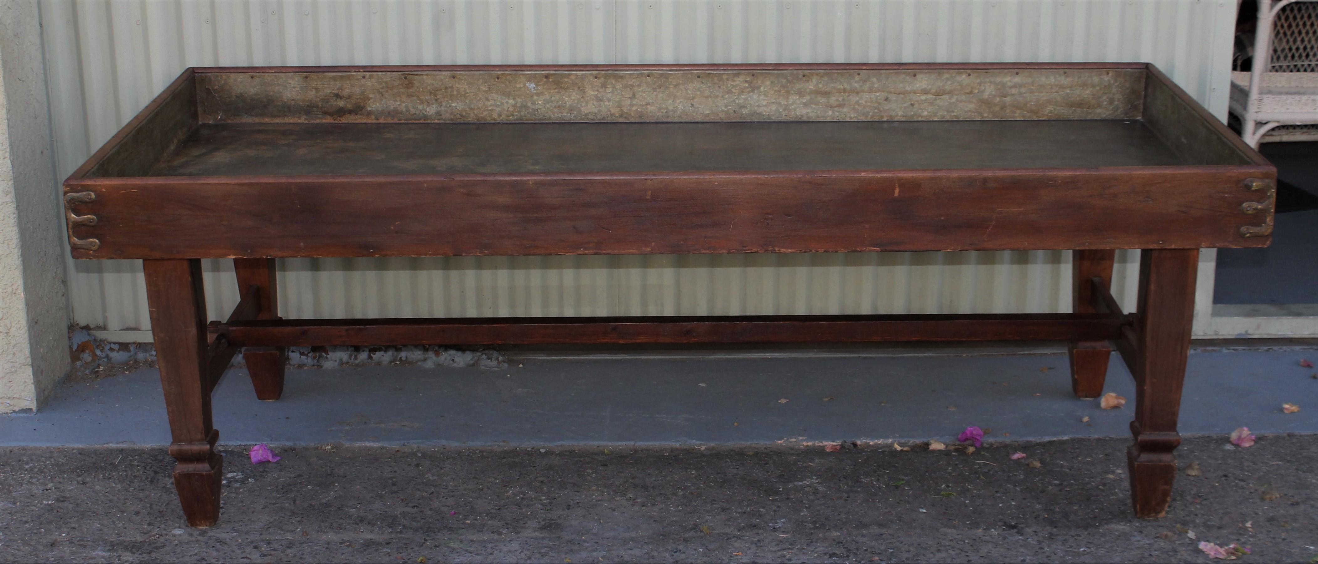 Cette table de triage en pin du 19ème siècle a une surface ancienne et un revêtement en étain qui est d'origine. Auparavant, les pieds se repliaient, mais ils ont été rendus fixes et robustes. Il possède toute la quincaillerie et les charnières